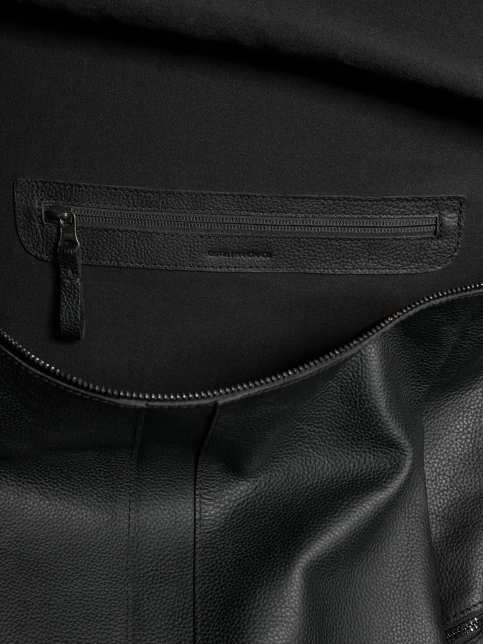 Interior shot of the Banteng leather backpack showing a zipped organizational pocket and luxurious lining.