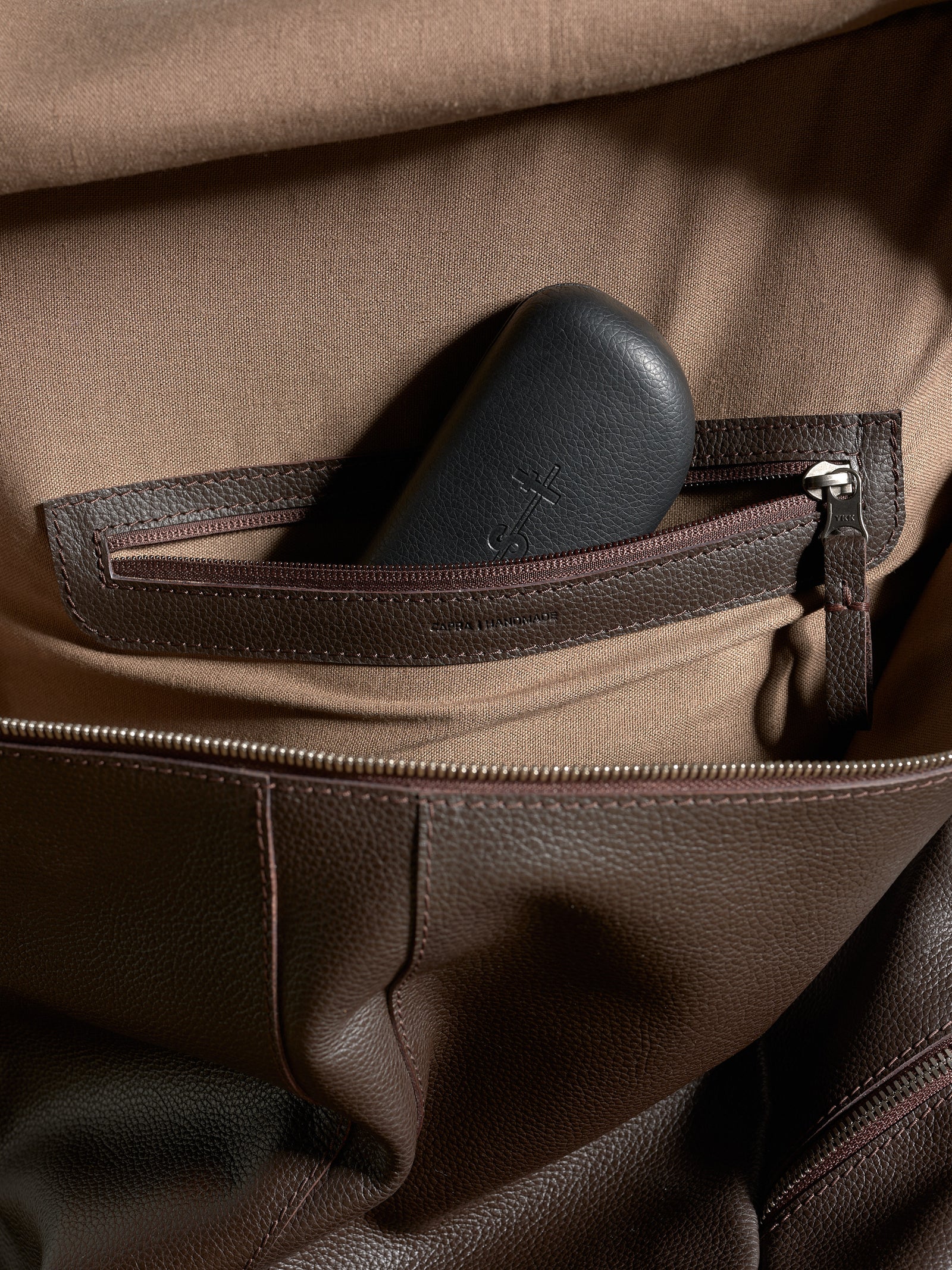 Interior zippered pocket detail for organization inside the Capra Leather dark brown backpack.