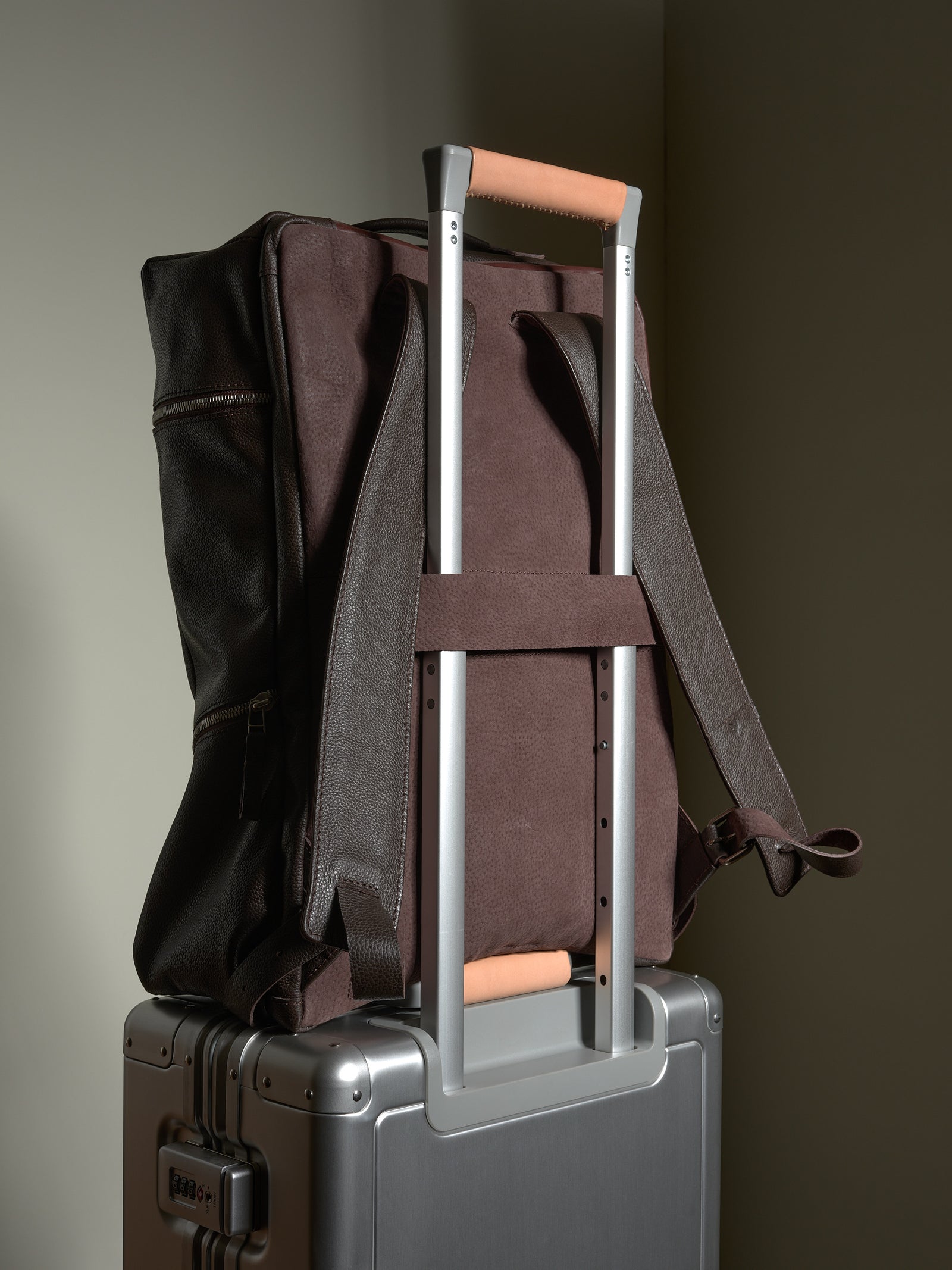 Dark brown leather travel backpack showing the convenient luggage pass-through strap for carry-on.