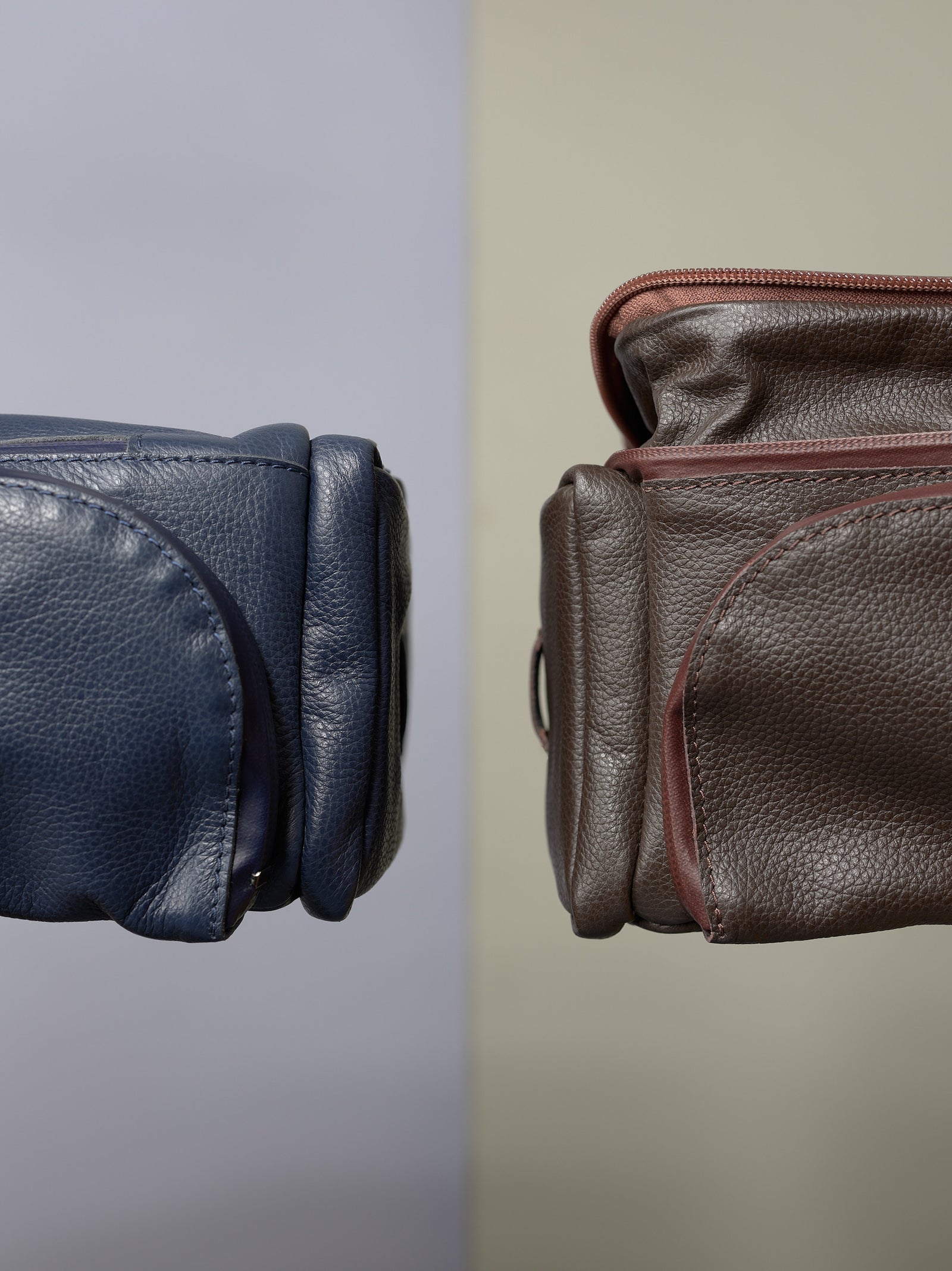 Close-up showing the textured blue and brown Capra Leather bike bags side by side, highlighting the premium leather.