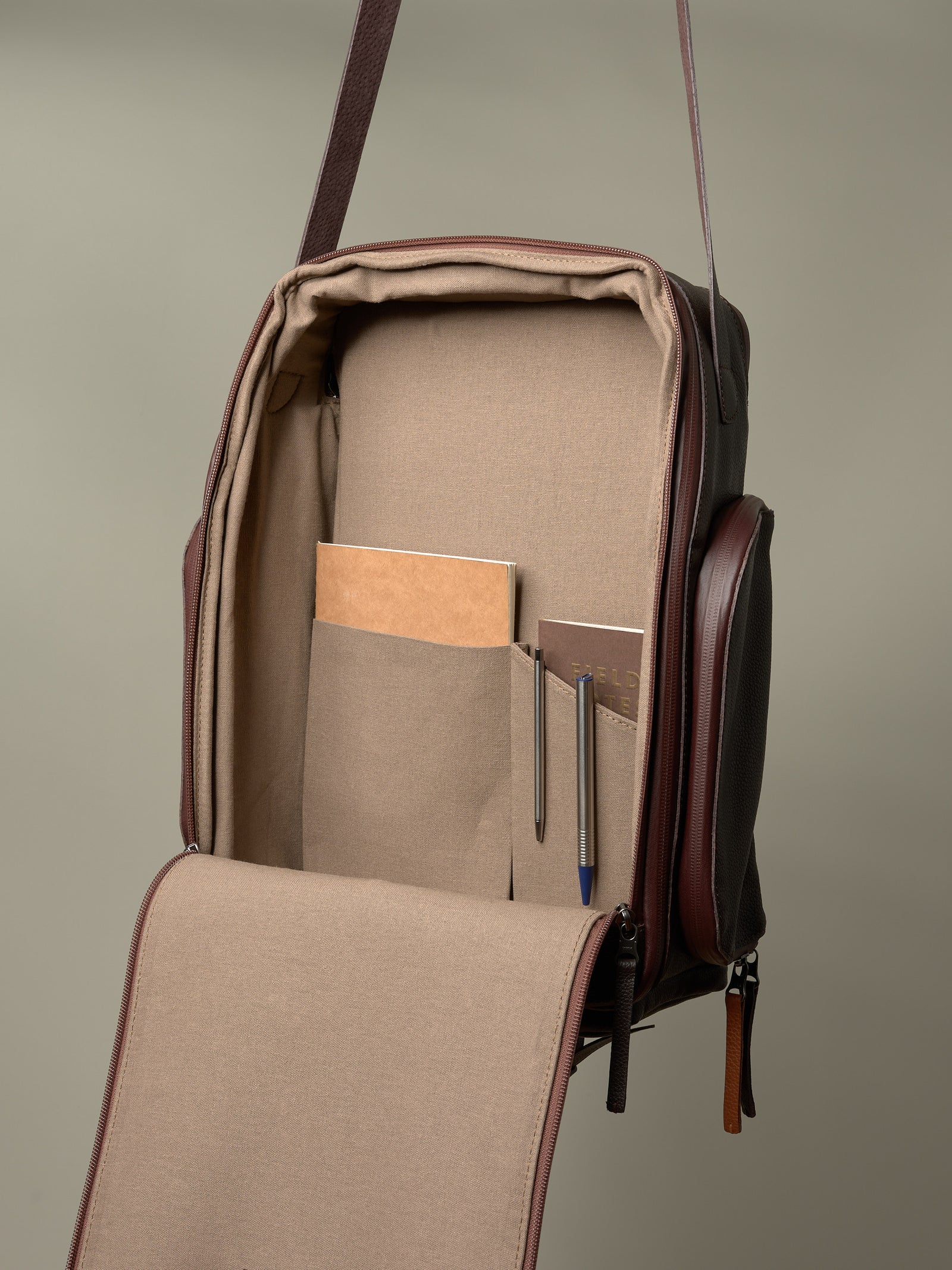 Open interior of the brown Capra Leather bag showing the canvas lining and organization pockets for gear.