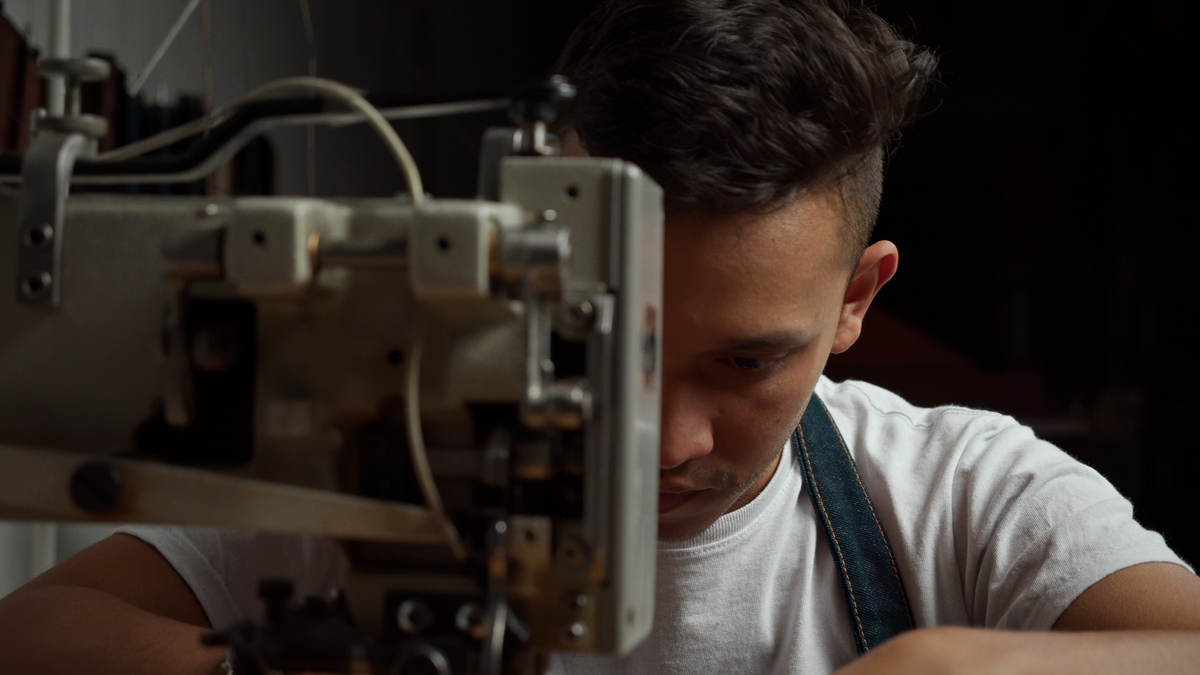 Artisan sewing leather at a machine in the Capra Leather studio in Bogotá, Colombia