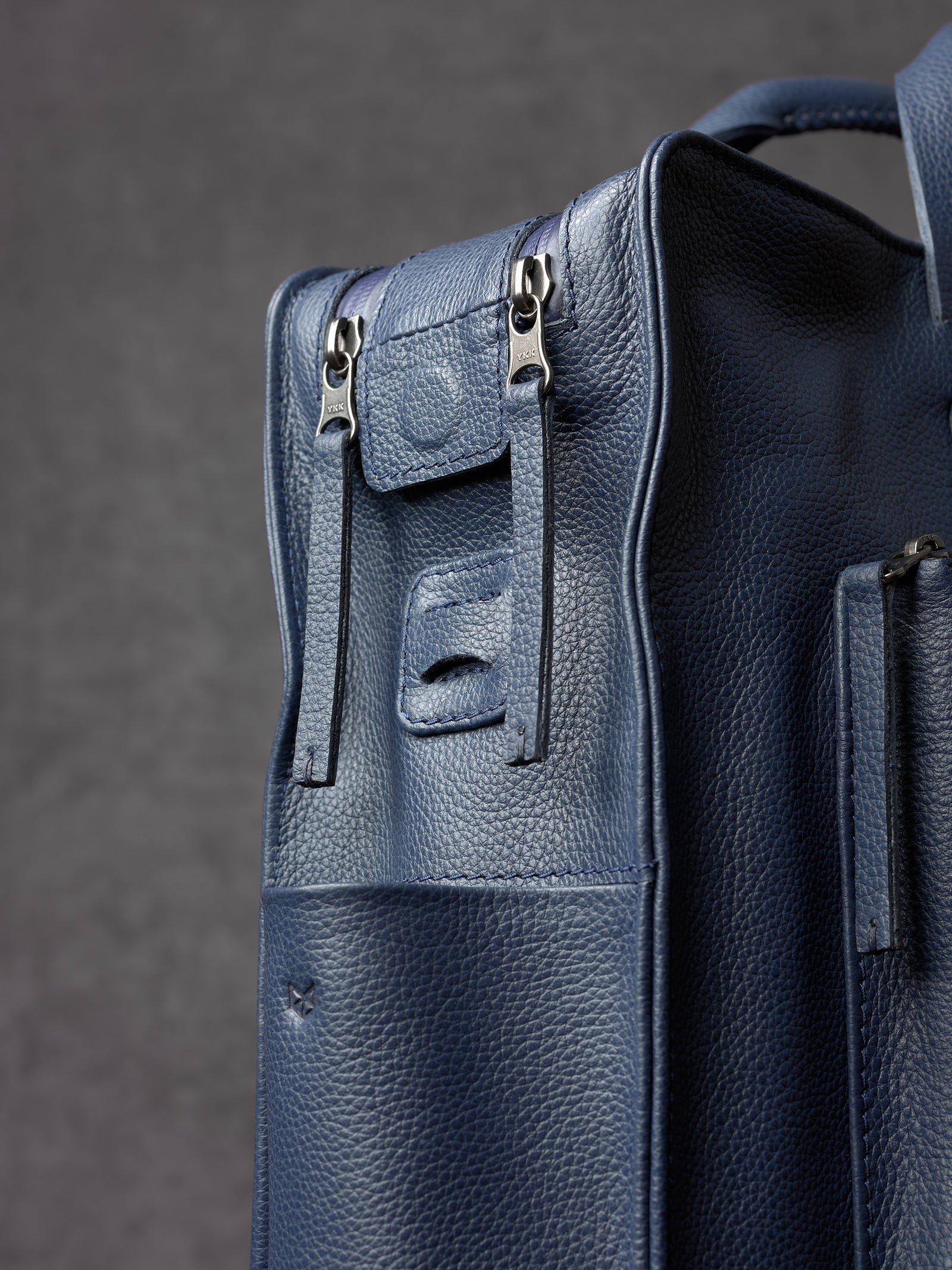 Close-up of premium metal YKK zippers and leather pulls on a Capra Leather bag.