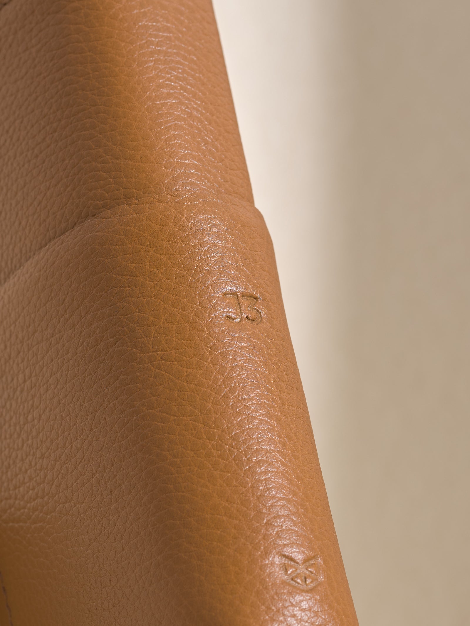 Close-up of tan full-grain leather with a personalized "J3" monogram, a thoughtful custom gift for men.