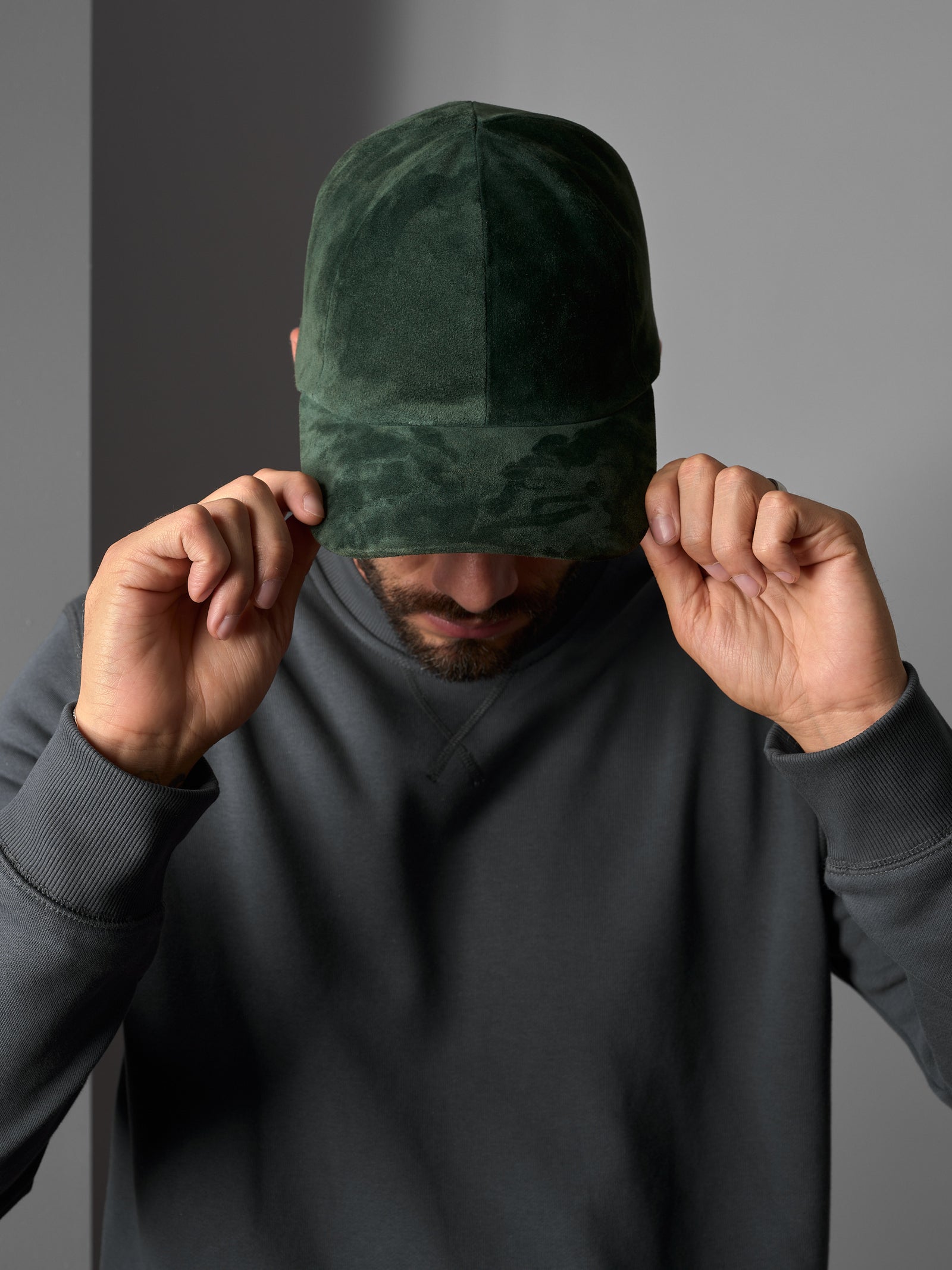 Man in a green suede Capra Leather cap and a gray sweatshirt.