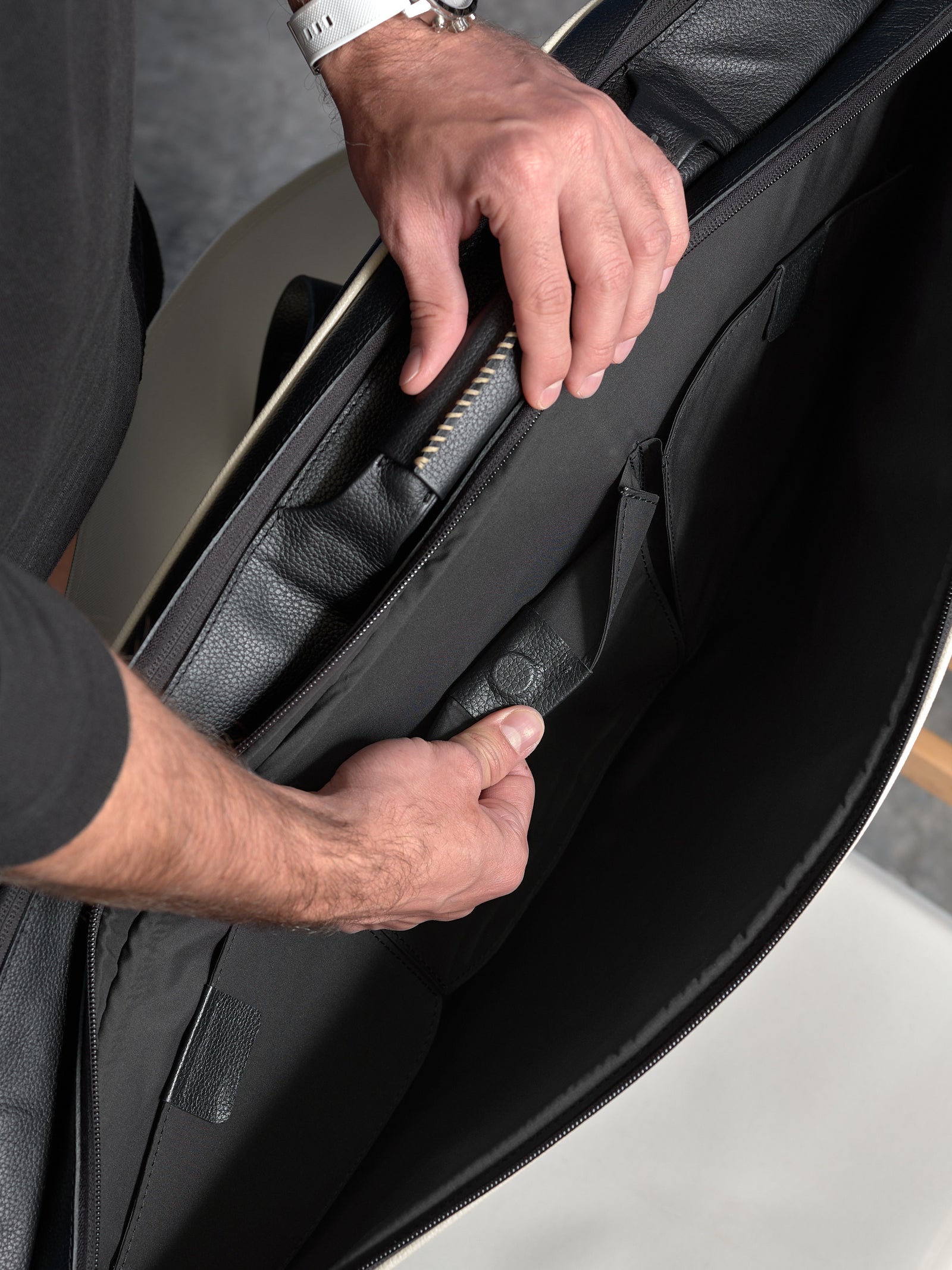 Top-down view of the organized internal pockets and heritage leather handle of a tennis bag.