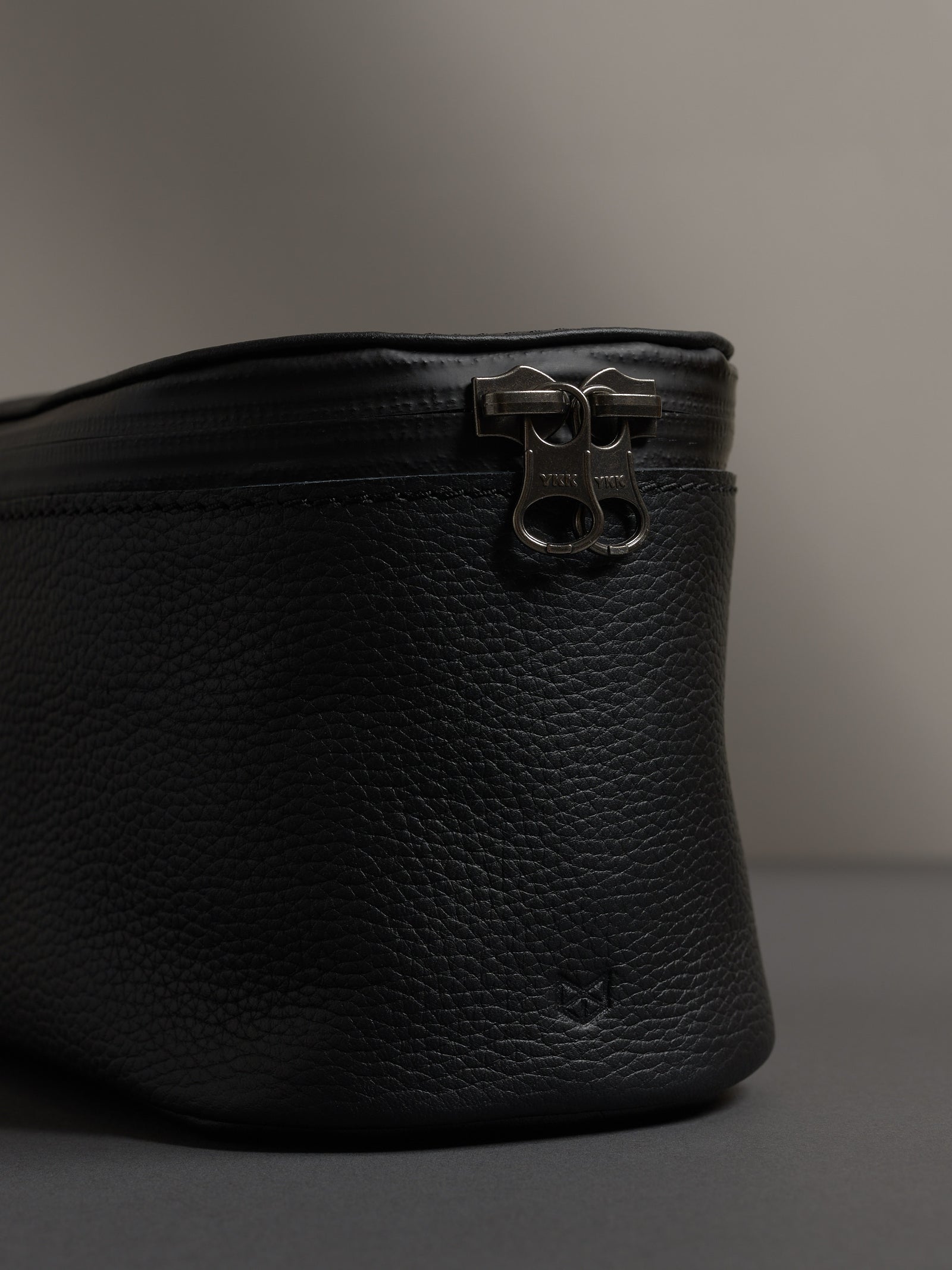 Detailed shot of the black leather texture and the premium YKK zipper hardware on the dopp kit.