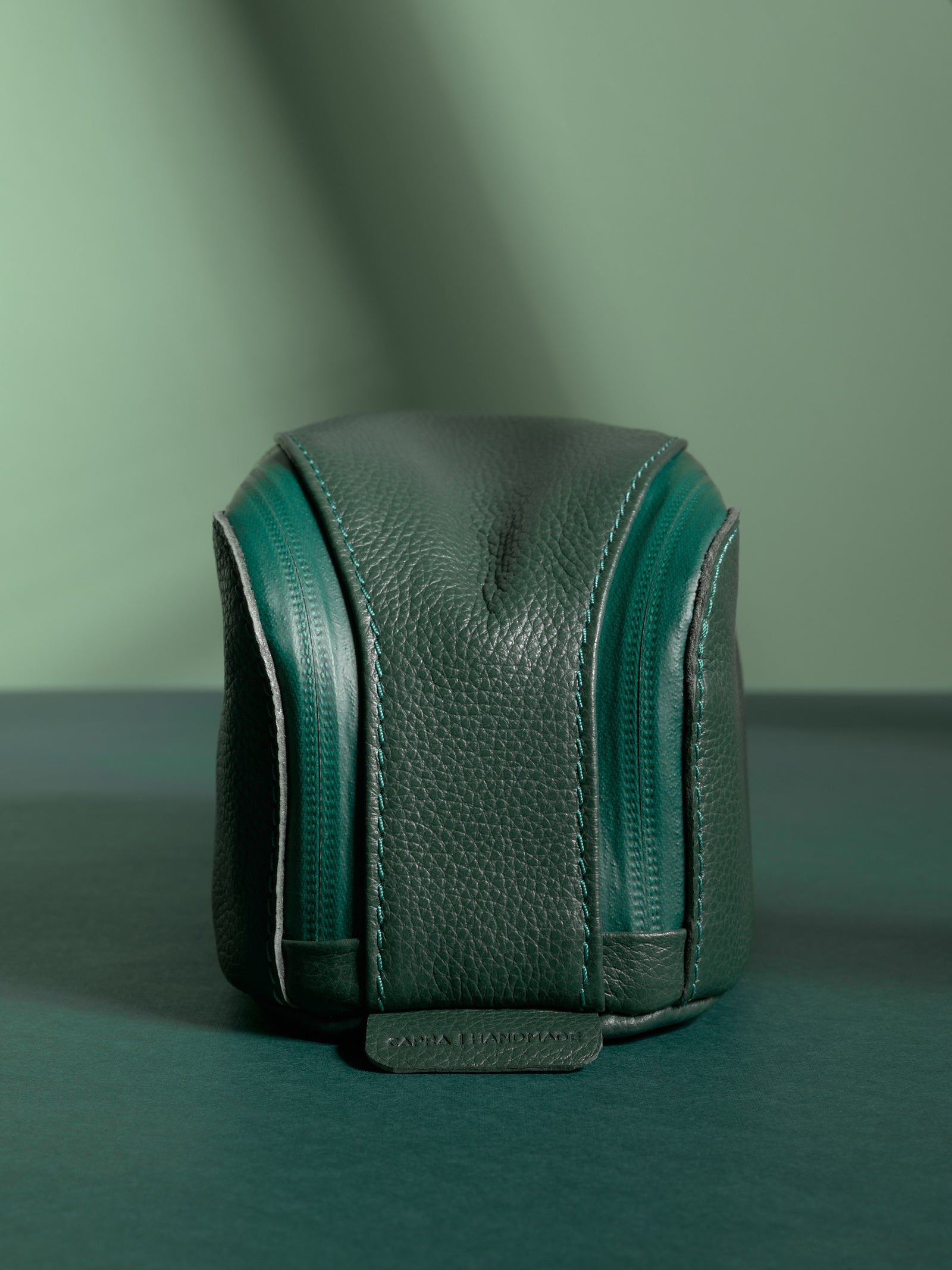Front view of the vertical green Capra Leather Toiletry Bag highlighting the twin zippers.