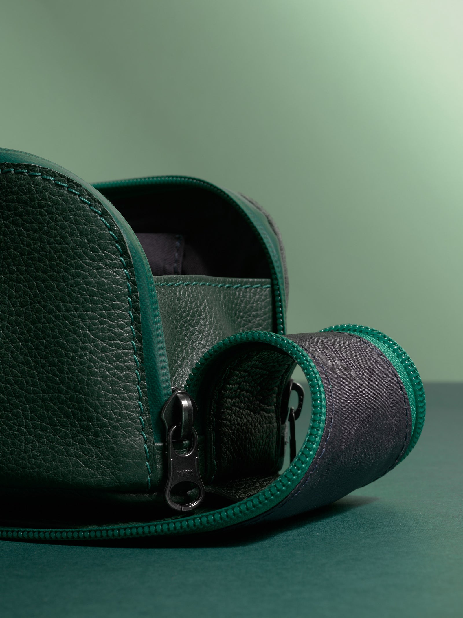 Close-up of the pebbled green Capra Leather texture and durable zipper pull detail.