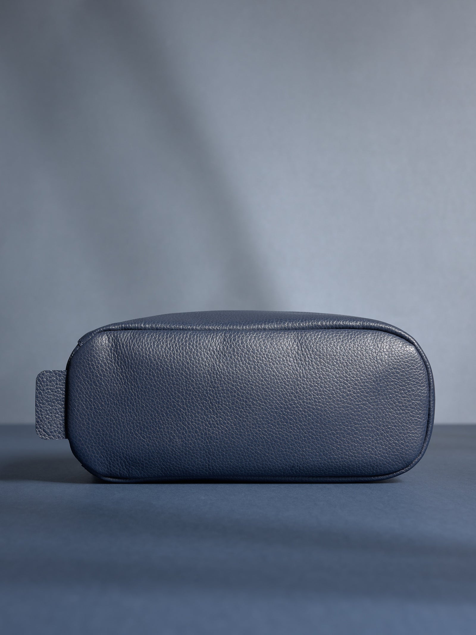 Bottom view of the personalized navy leather toiletry bag, highlighting its durable, flat base.