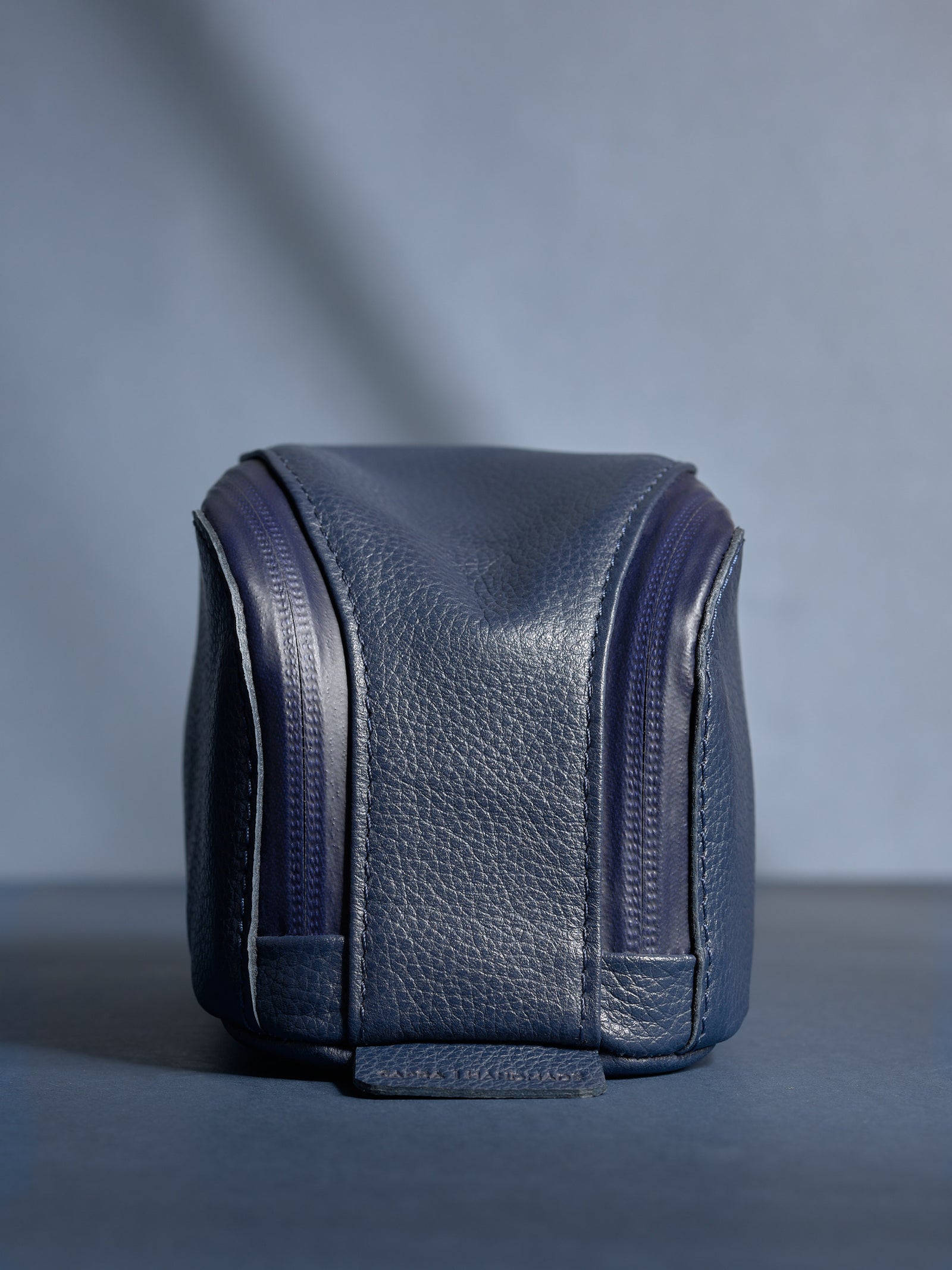 Close-up of personalized navy Capra leather toiletry bag standing upright, showing the fine grain and dual zippers.