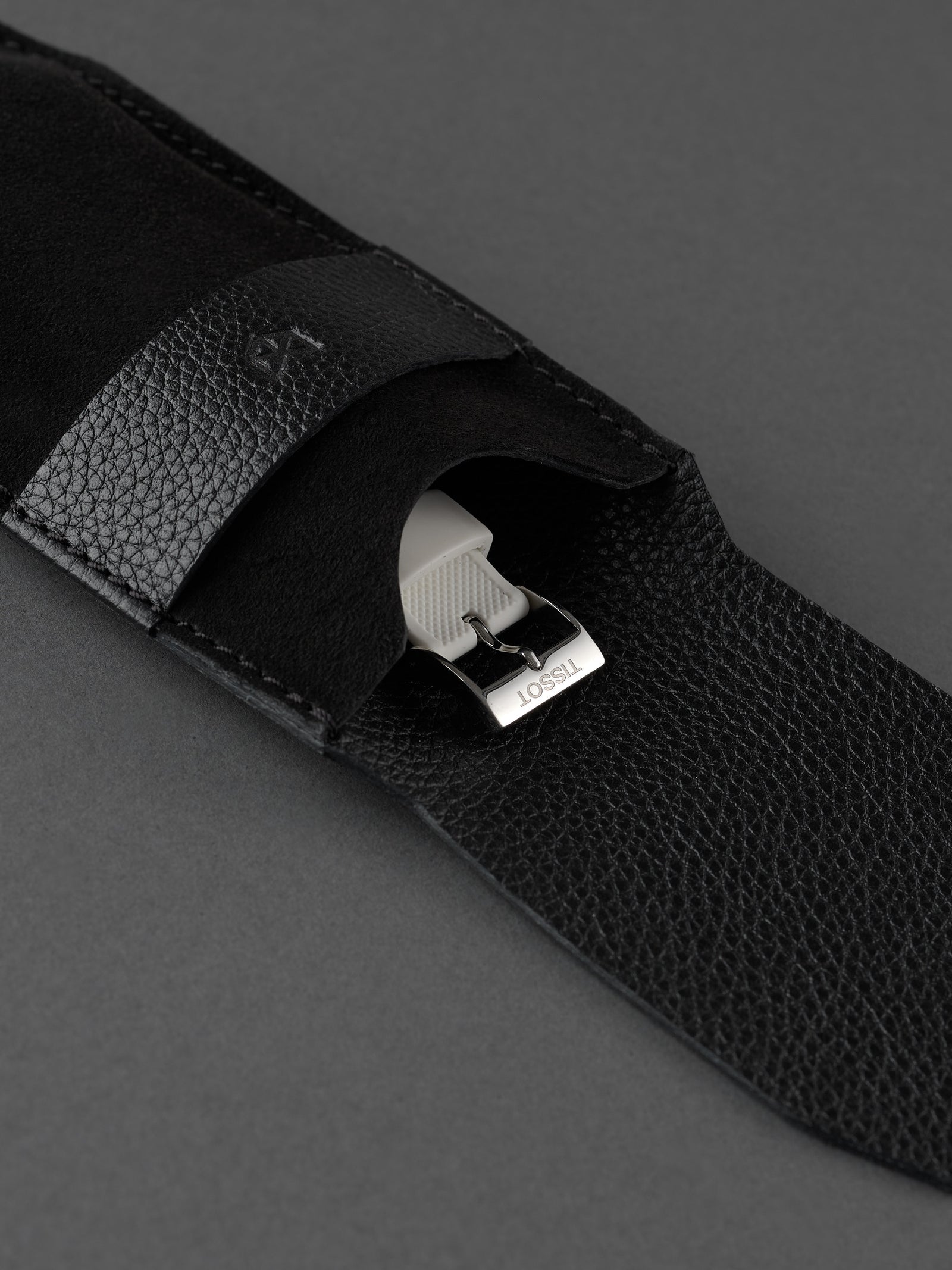 White watch strap and buckle safely stored inside a Capra Leather black suede pouch.