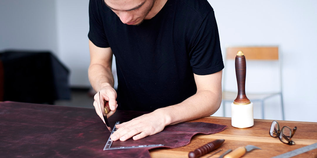 Cutting leather by hand at a workbench in the Capra Leather studio