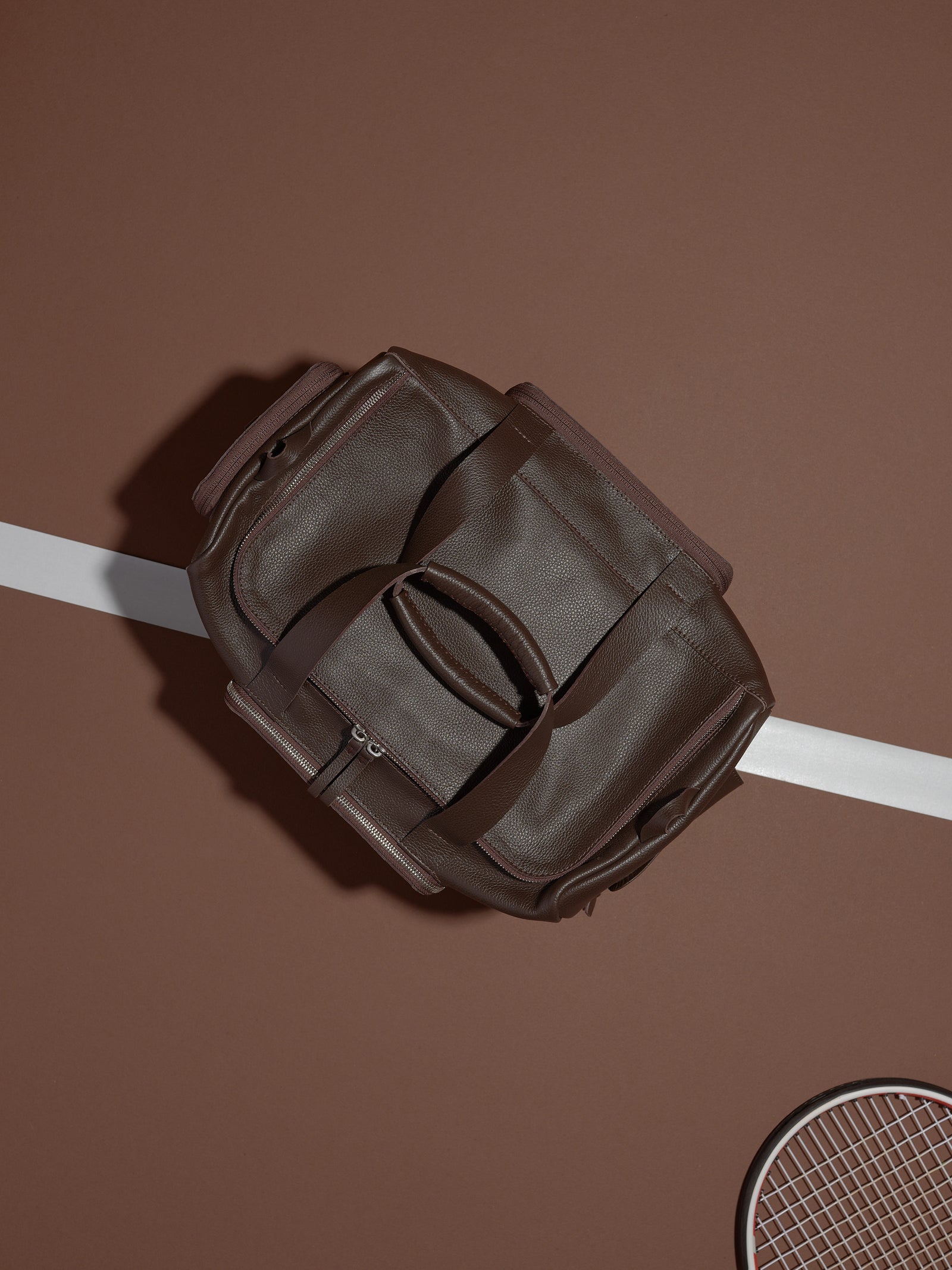 The Ventra Holdall duffle bag lying open on a tennis court, with a white line and tennis racket visible.