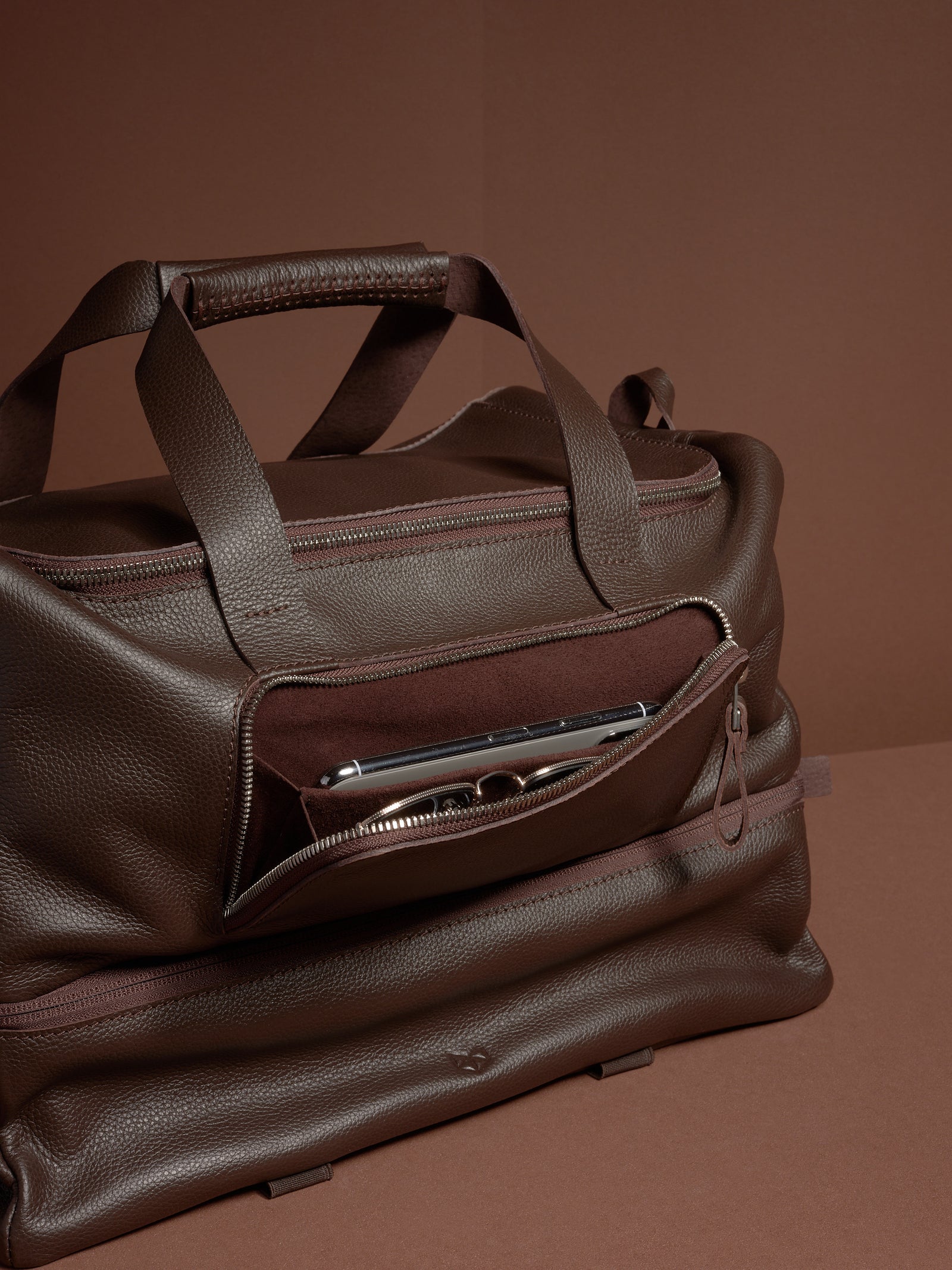 The Ventra Holdall bag with a front pocket unzipped, showing a smartphone and glasses inside.