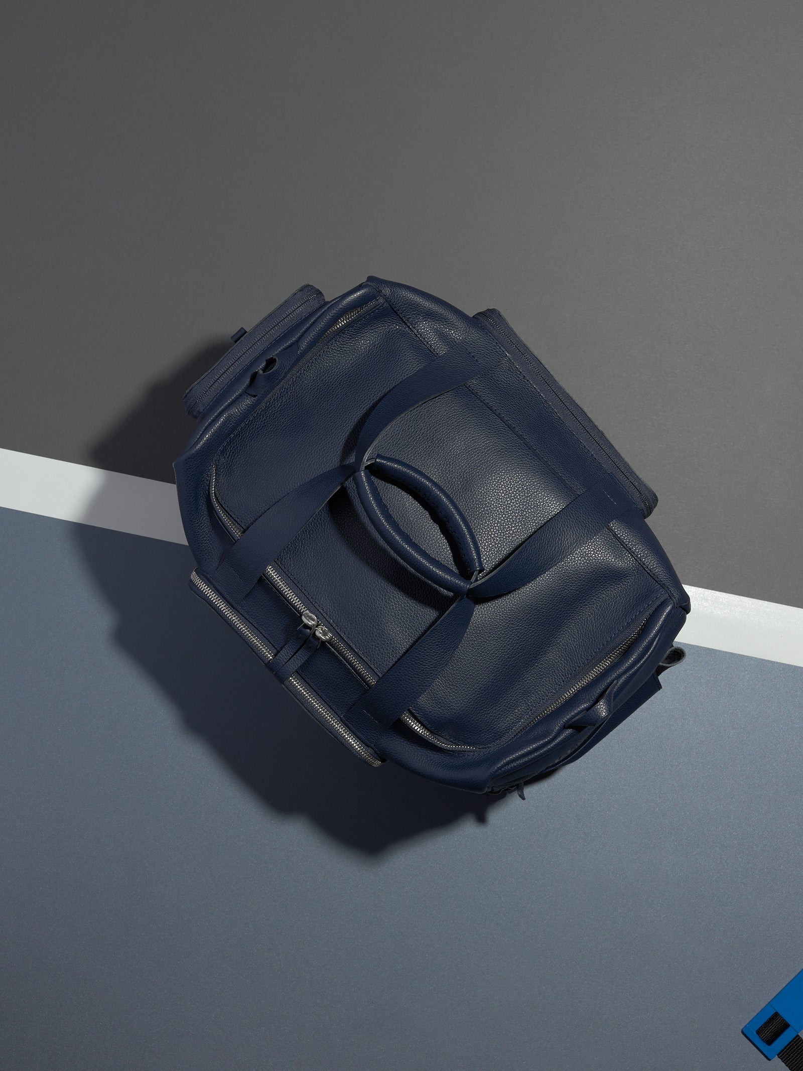 The Ventra Holdall duffle bag lying on a tennis court with a white line and blue background.
