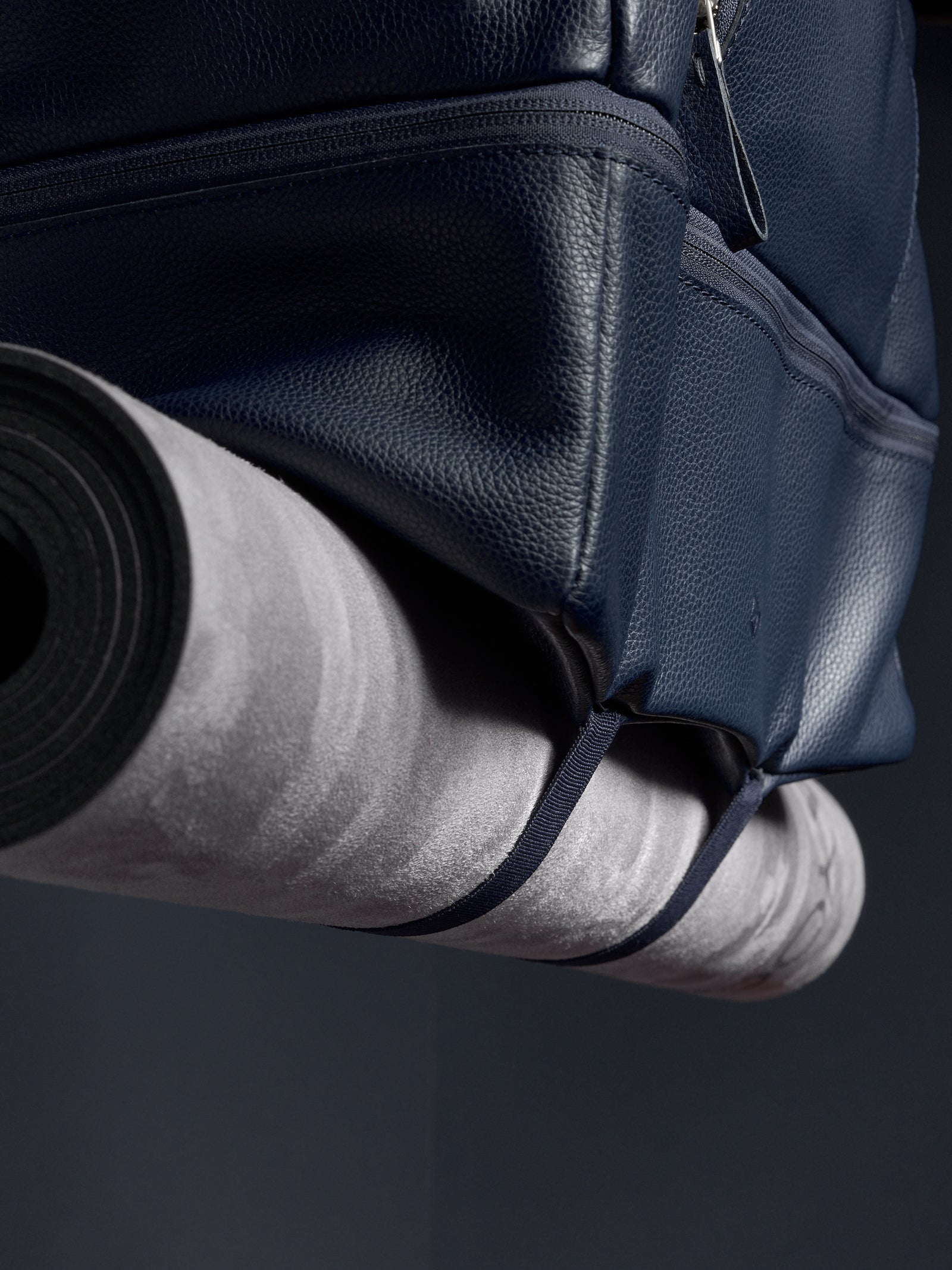 Close-up of the Ventra Holdall's bottom straps holding a yoga or exercise mat.