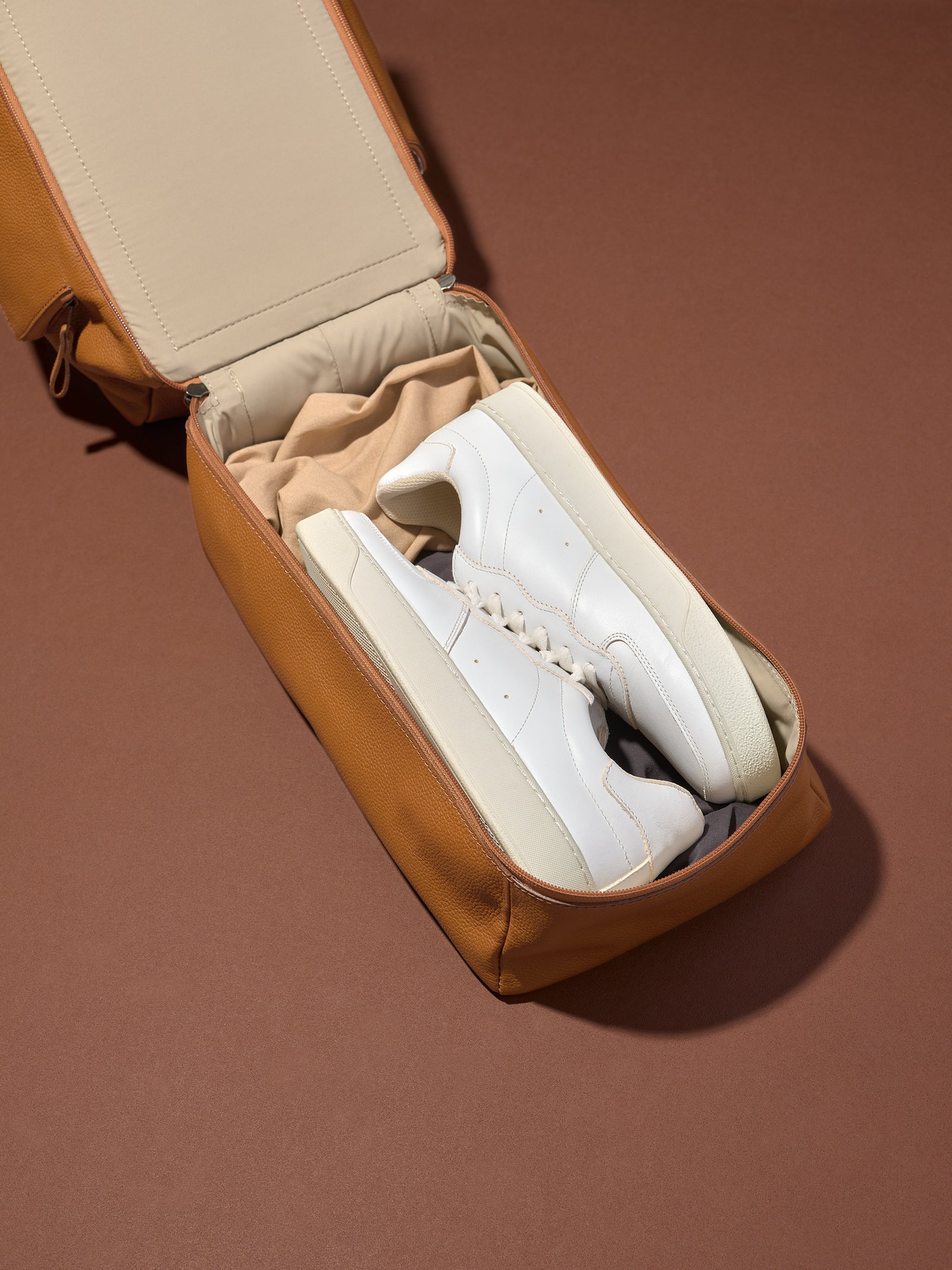 The Ventra Holdall's separate, ventilated shoe compartment is open, holding a pair of white sneakers for travel or the gym.