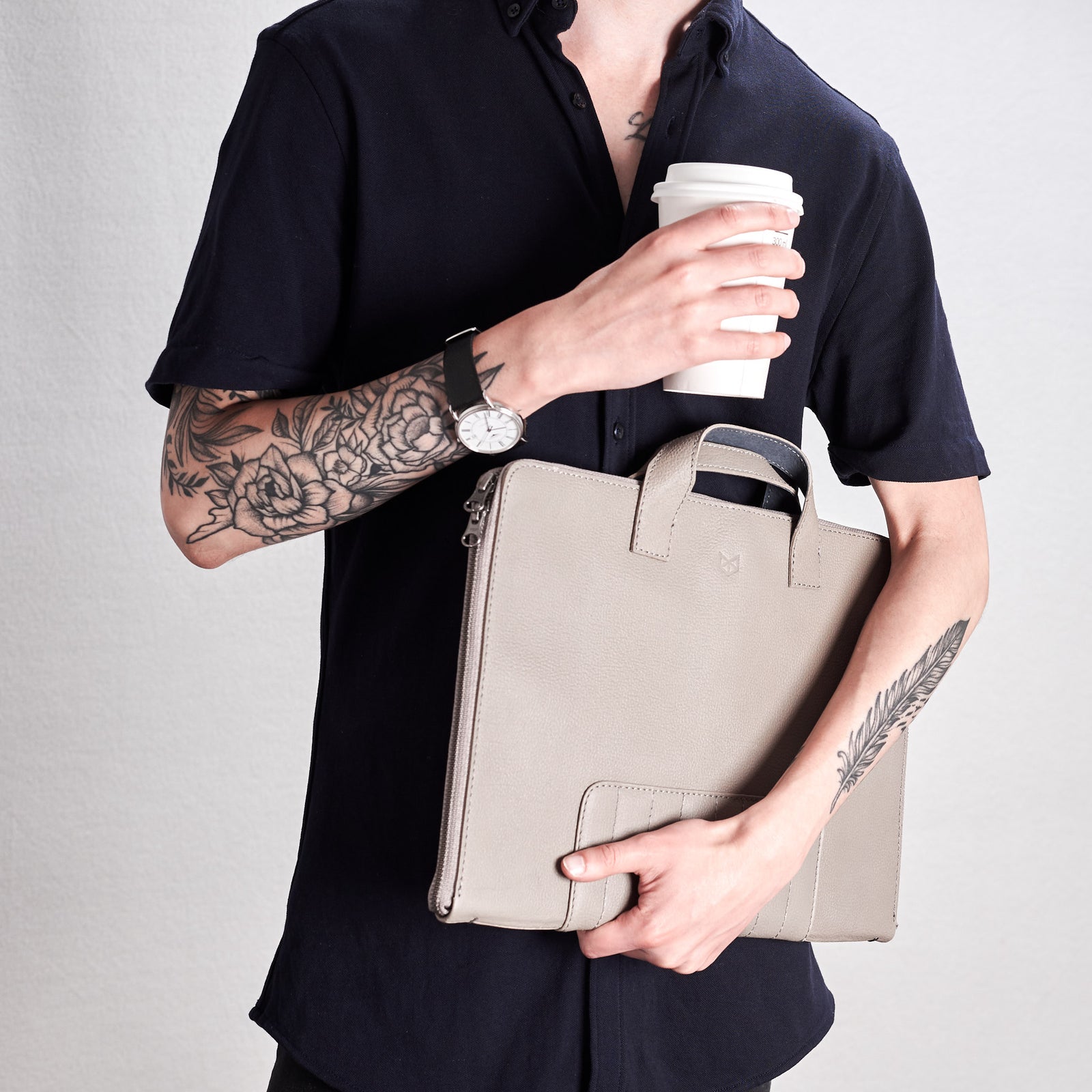 Grey Biker portfolio style picture. Holding portfolio and coffee cup.