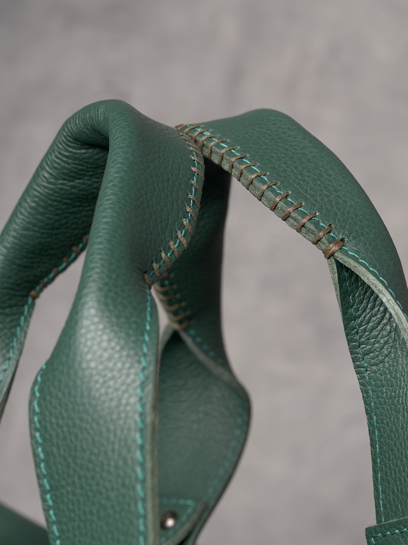 Close-up of the reinforced duffle bag handles featuring intricate hand-stitched detailing in a contrasting thread.