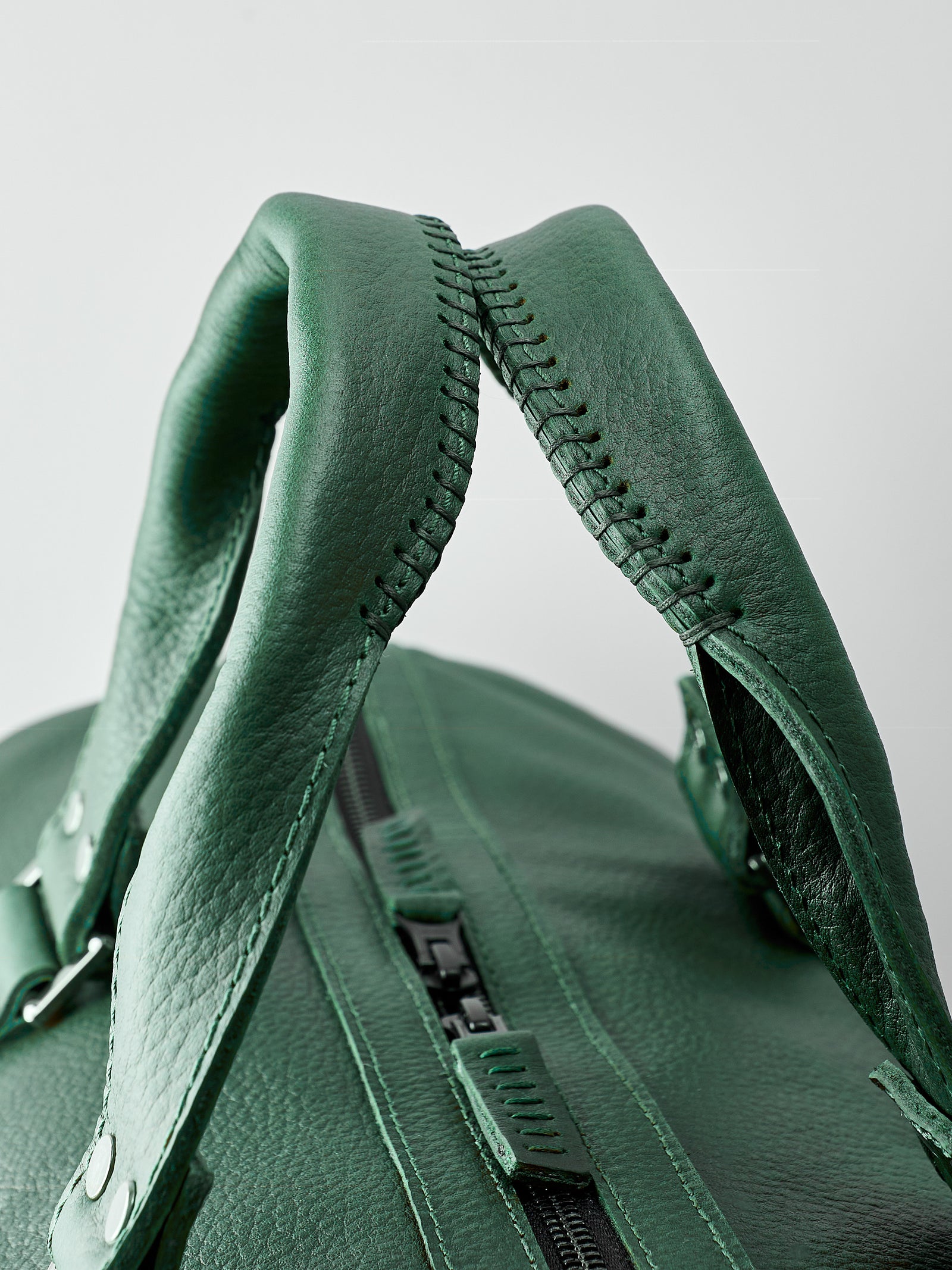 Hand stitched handles. Green leather athletic duffle bag for weekend