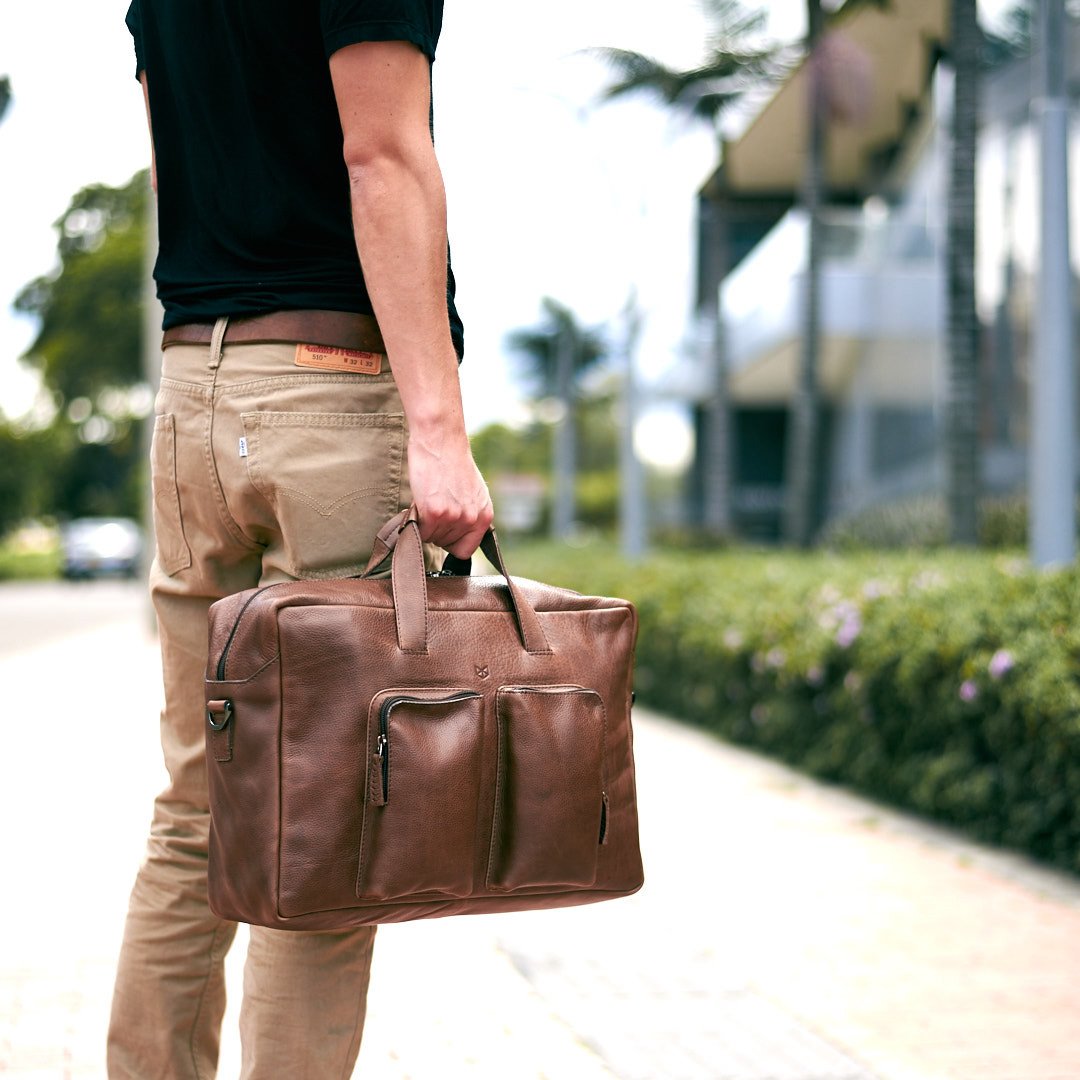 Man holding a brown leather bag. Equz Messenger Bag by Capra Leather. 