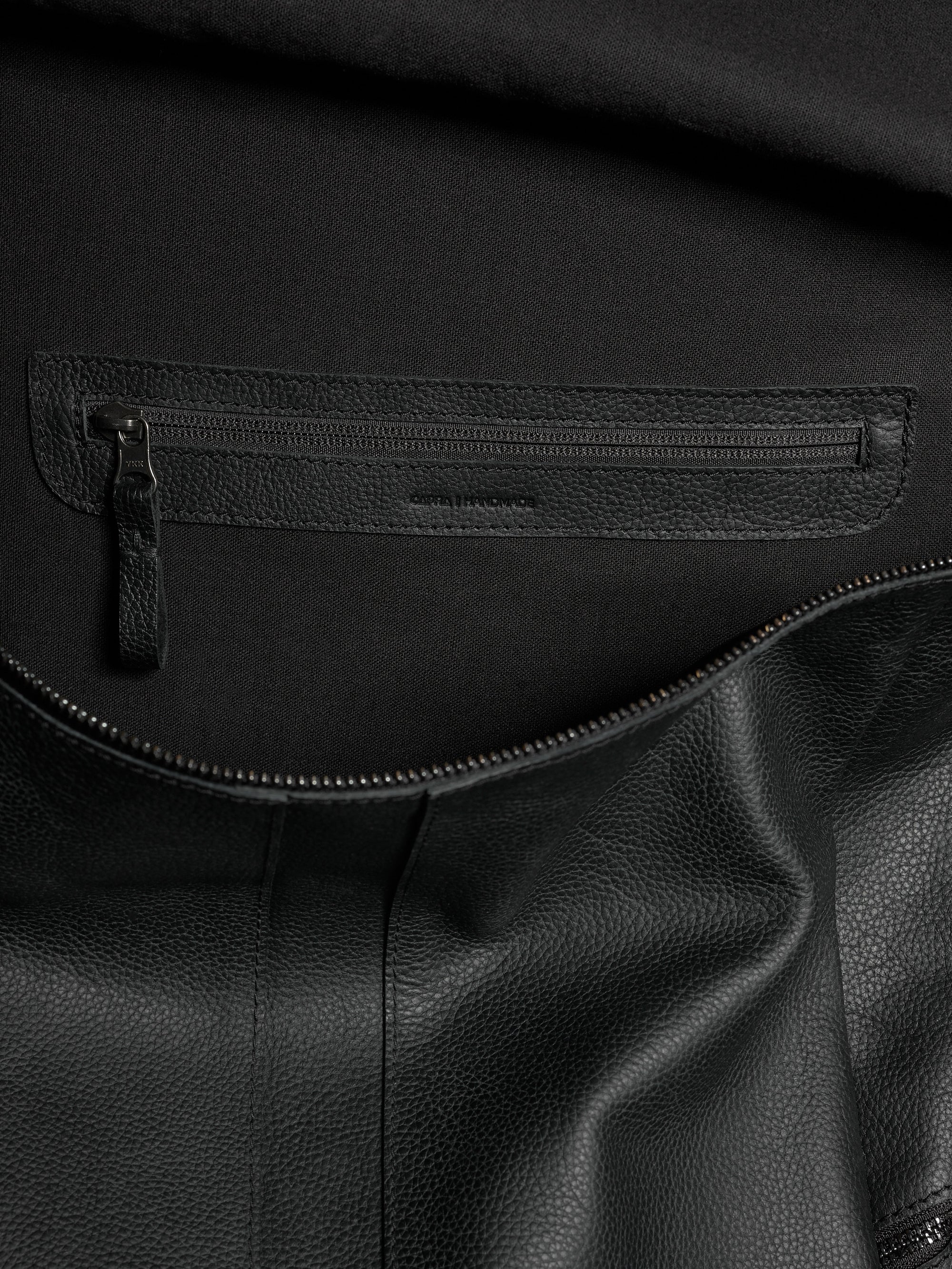 Interior shot of the Banteng leather backpack showing a zipped organizational pocket and luxurious lining.