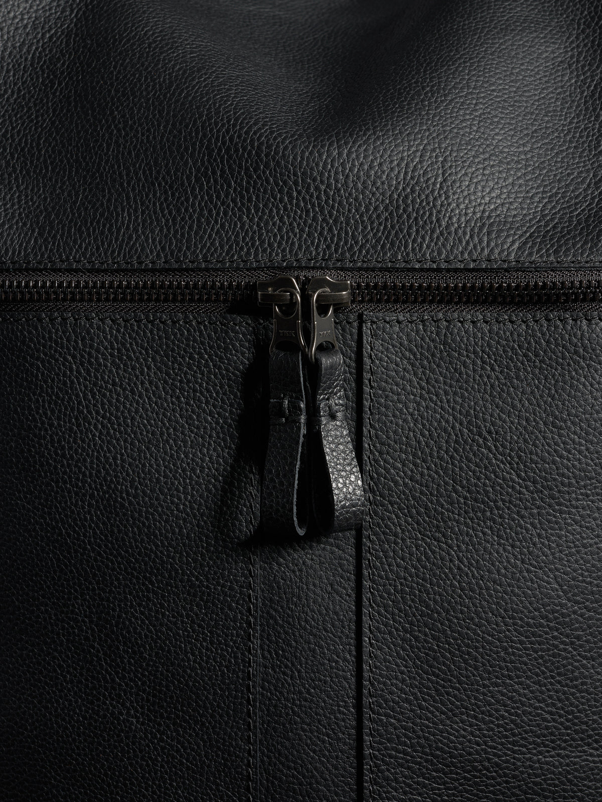 Detailed close-up of the pebbled full-grain black leather texture and the robust zipper on a Capra Leather bag.