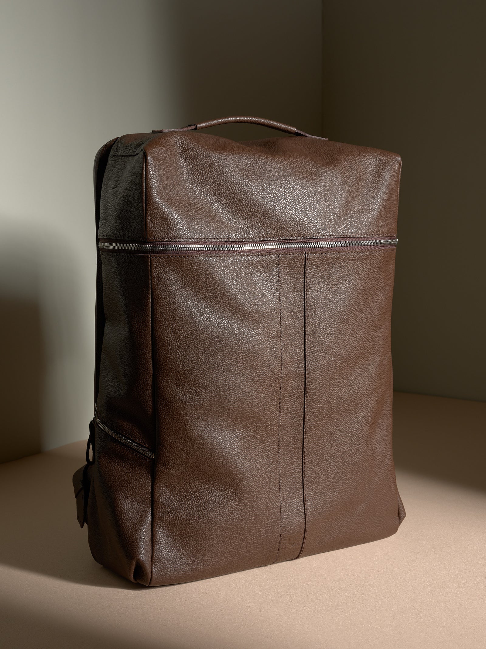 Front view of the square brown full-grain leather Capra Leather Banteng backpack with silver zippers.