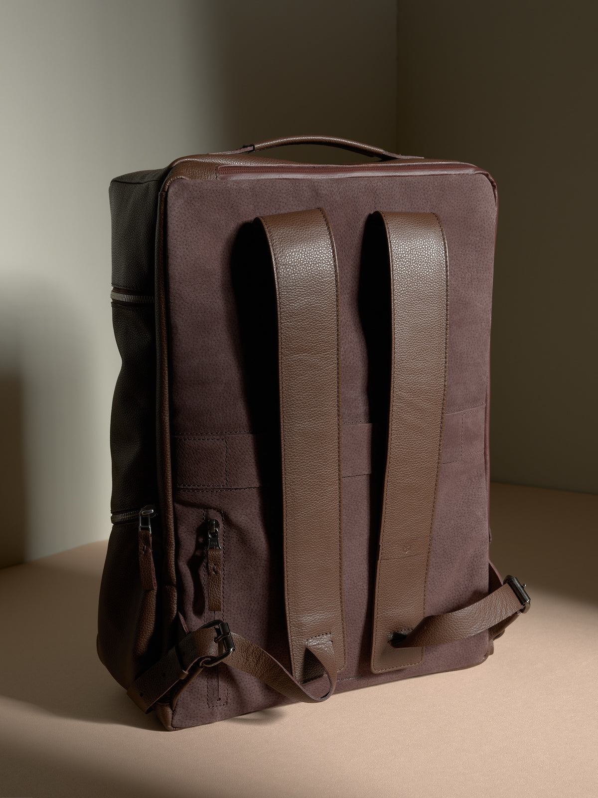 Back view of the Capra Leather backpack showing the dark brown suede panel and leather shoulder straps.