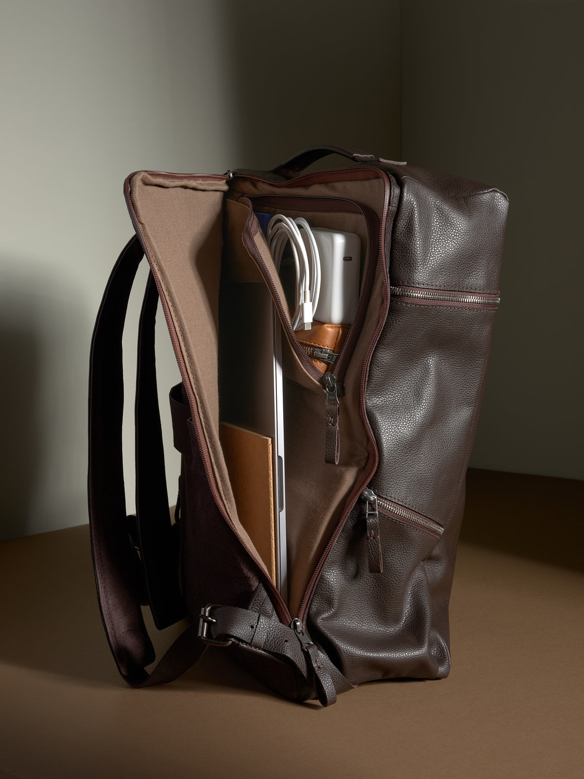 Dark brown leather laptop backpack interior showing tech sleeve and organization for electronics.