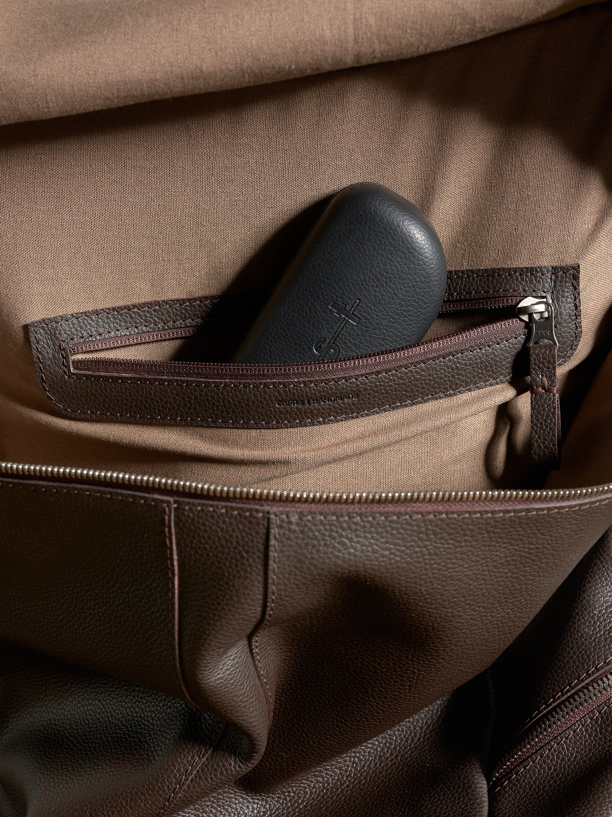 Interior zippered pocket detail for organization inside the Capra Leather dark brown backpack.