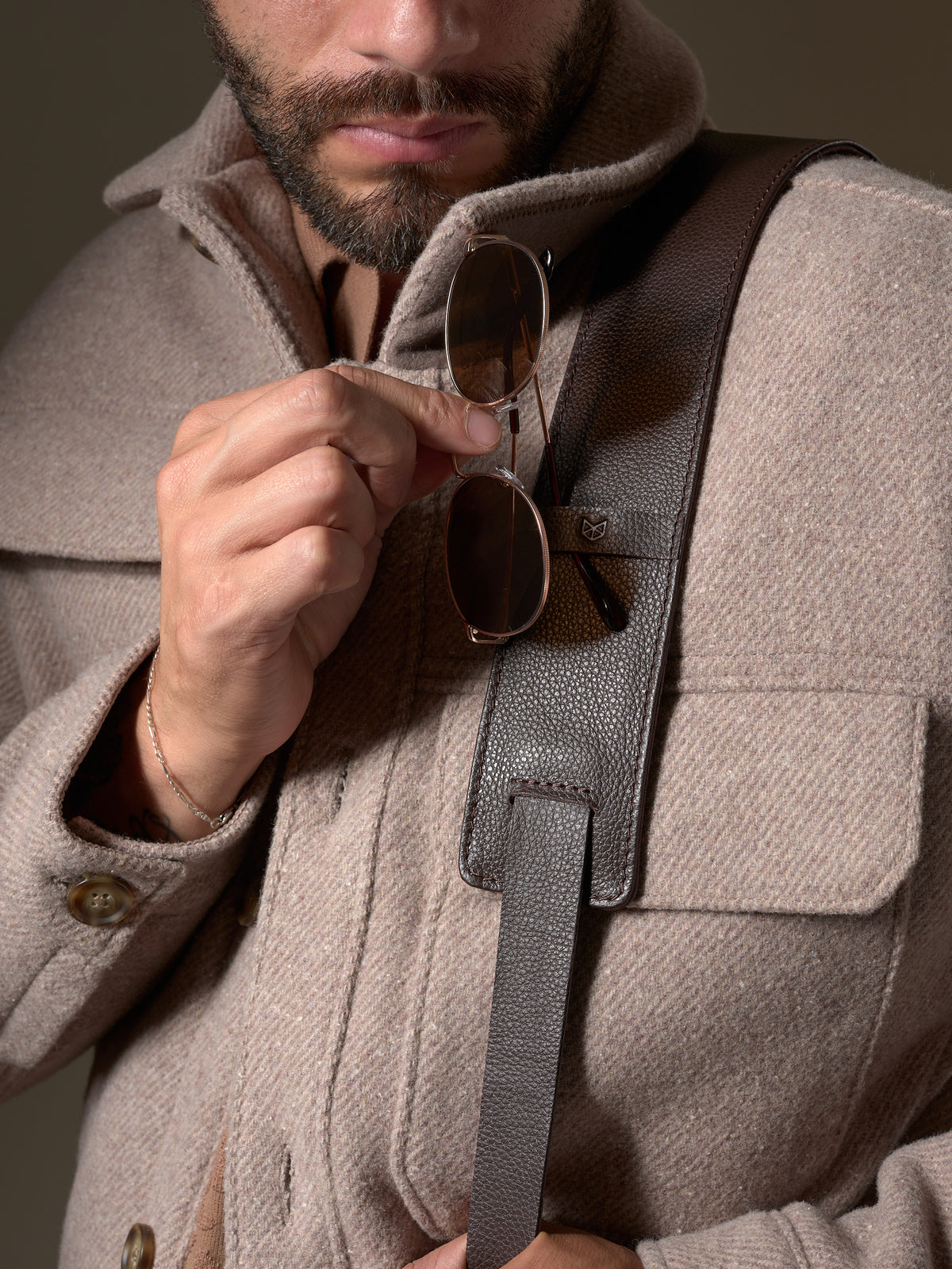 Close-up of the dark brown leather shoulder strap and subtle Capra Leather logo detail.
