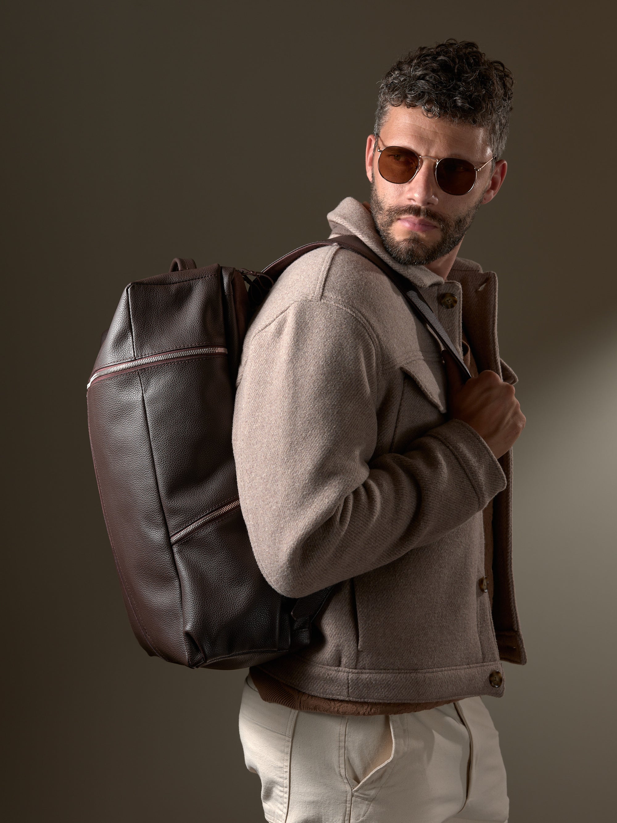 Man wearing the stylish Capra Leather Banteng; a premium men's dark brown leather backpack.