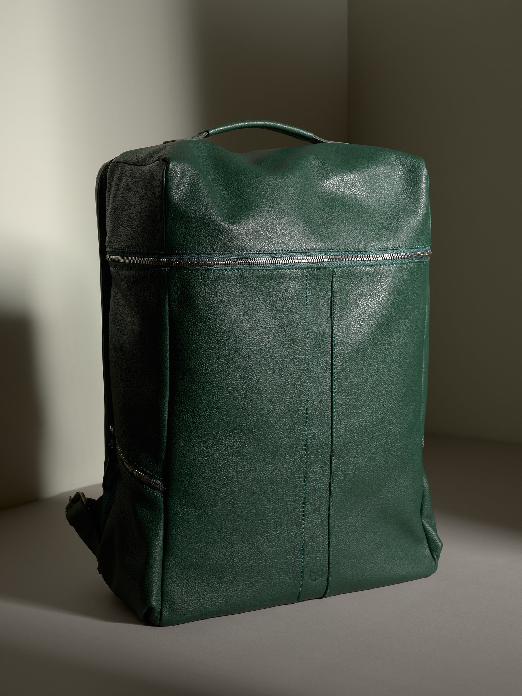 Full front view of the premium Capra Banteng Green Leather Backpack with dual front zippers.