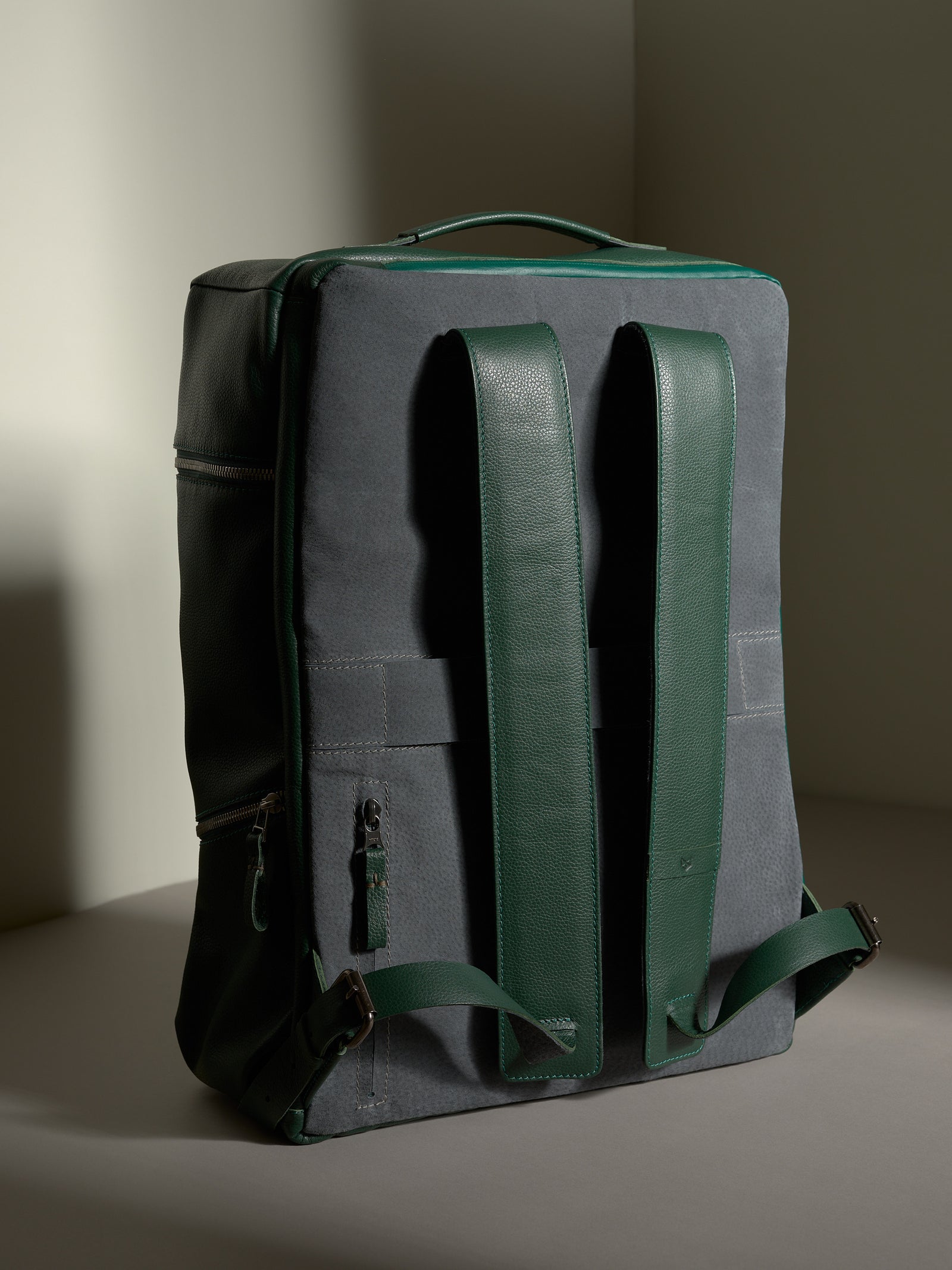 Back view of the Capra Banteng green and gray leather backpack, showing the full design and thick shoulder straps