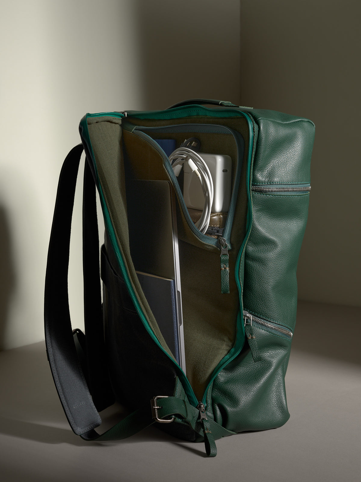 Main compartment of the green leather Capra Banteng backpack, revealing smart storage for a laptop and tech gear.
