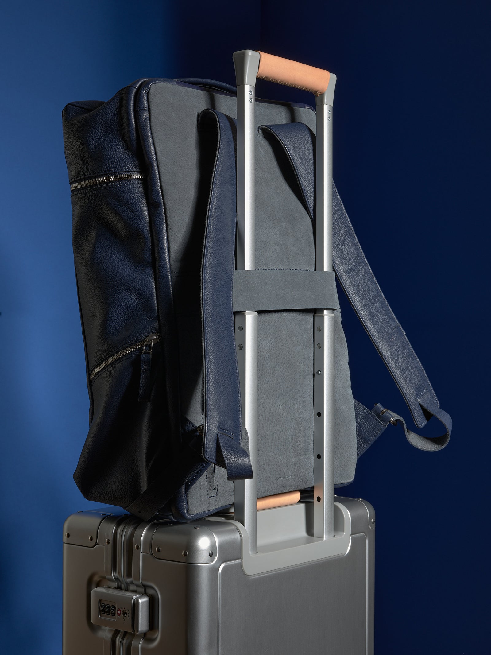 The Banteng backpack's built-in luggage strap securely slipped over the handle of a rolling suitcase for easy travel.