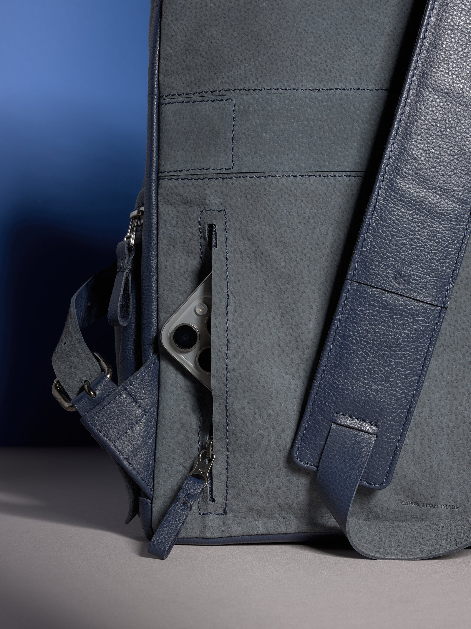 A black leather wallet being slipped into the secure, hidden anti-theft pocket on the back of the Banteng backpack.