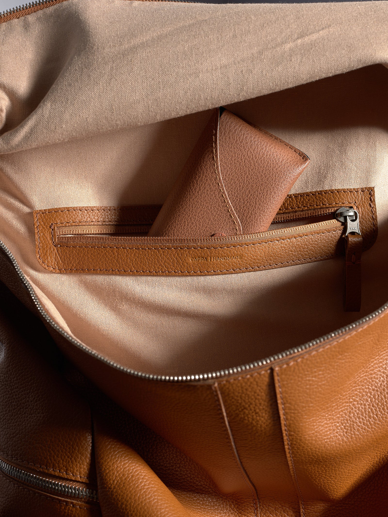 Interior shot of the Capra backpack showing a small leather accessory tucked into a zippered pocket.