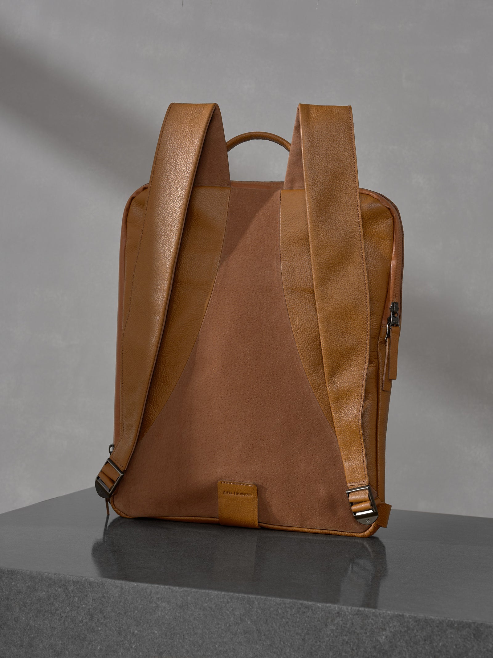 Rear view of the Capra Leather tan backpack showing the comfortable wide leather shoulder straps and a smooth brown suede back panel.