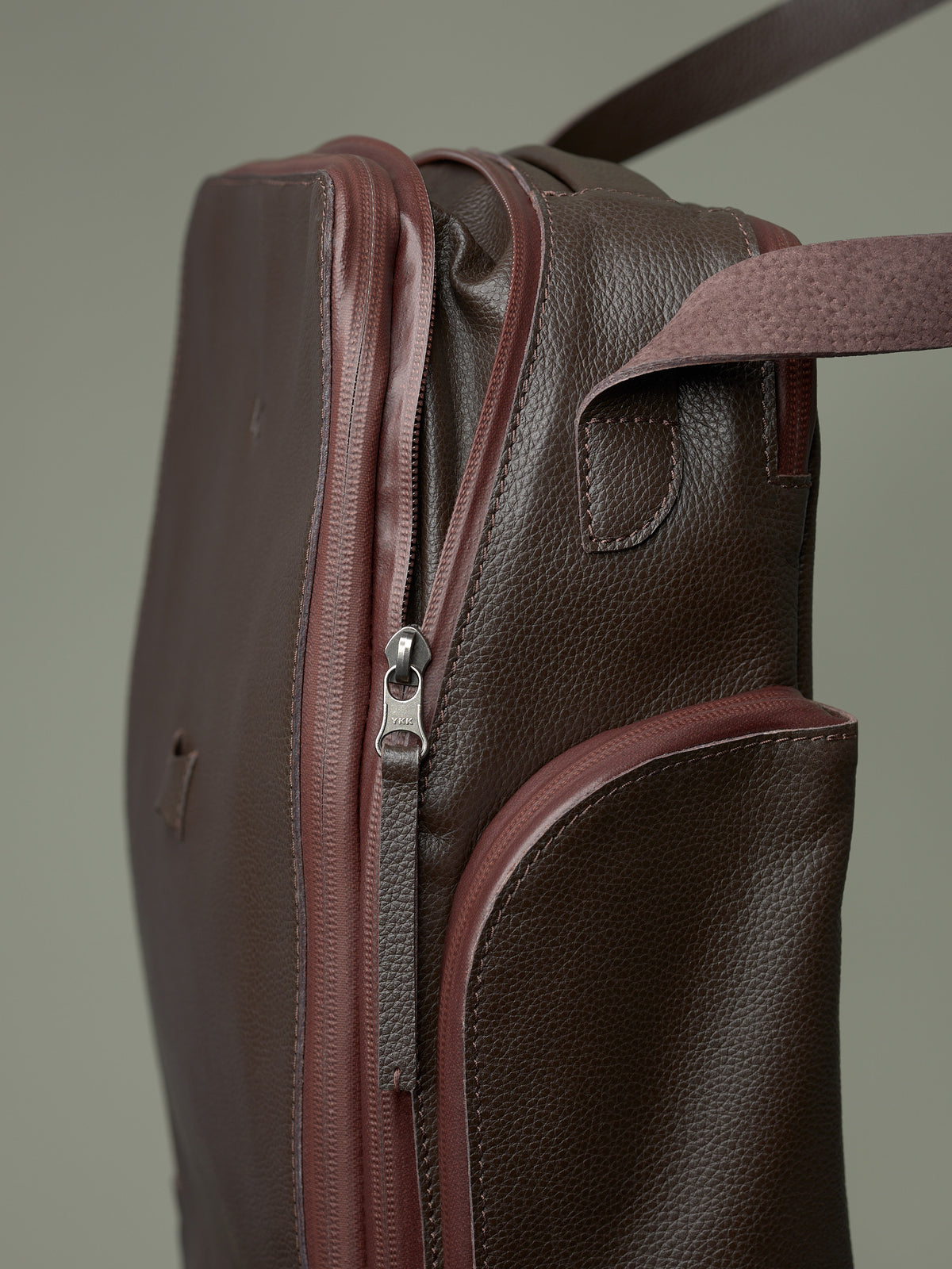 Detail of the brown leather bike bag showing the quality YKK zipper closure and the rich pebbled texture of the leather.