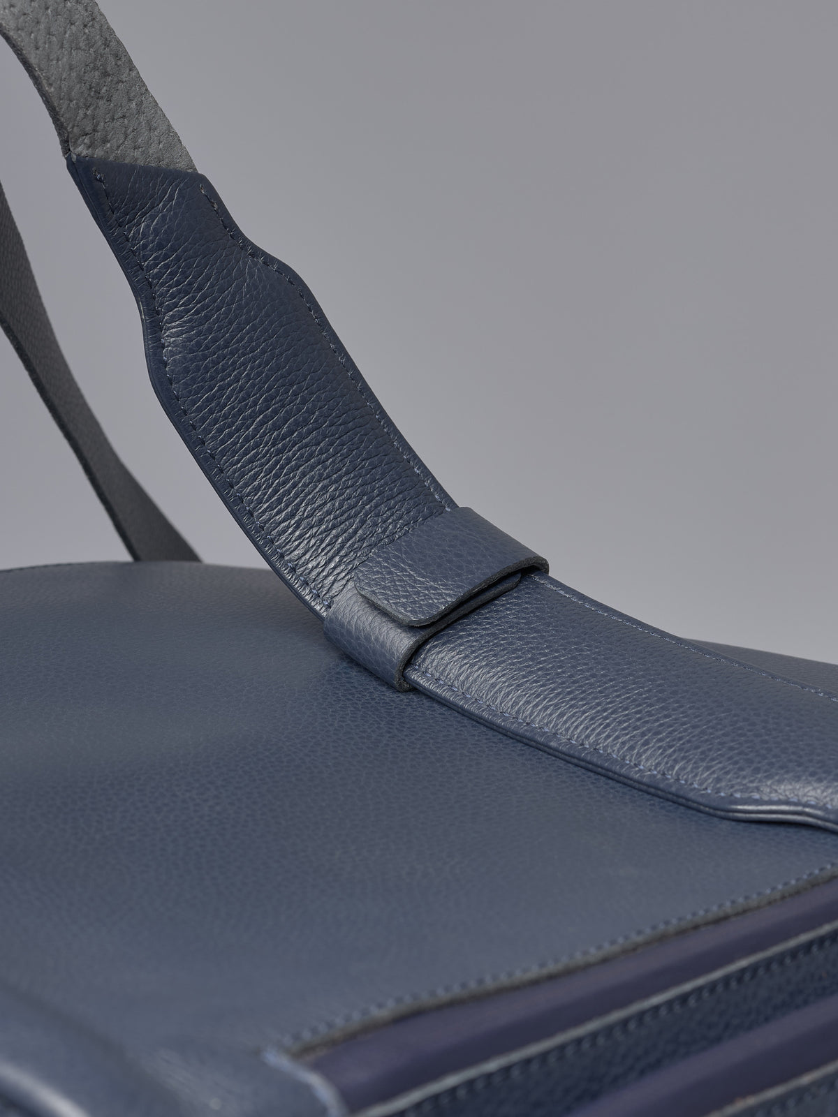 Detailed close-up of the adjustable blue leather shoulder strap on the Capra Leather versatile bag.