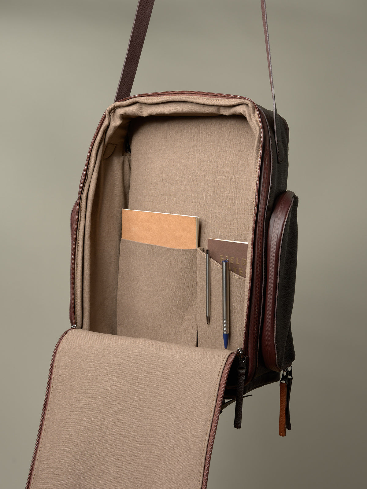 Open interior of the brown Capra Leather bag showing the canvas lining and organization pockets for gear.