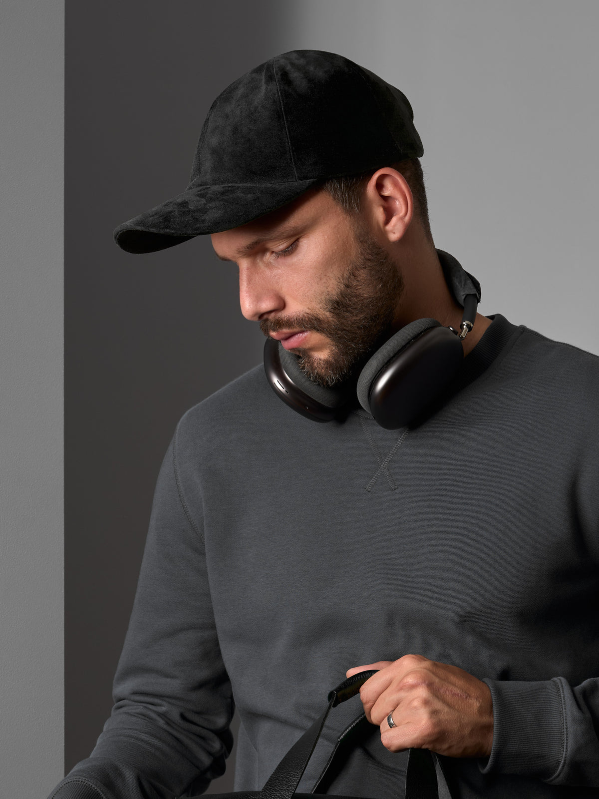 Man wearing a black suede Capra Leather cap and black headphones with a gray sweatshirt.