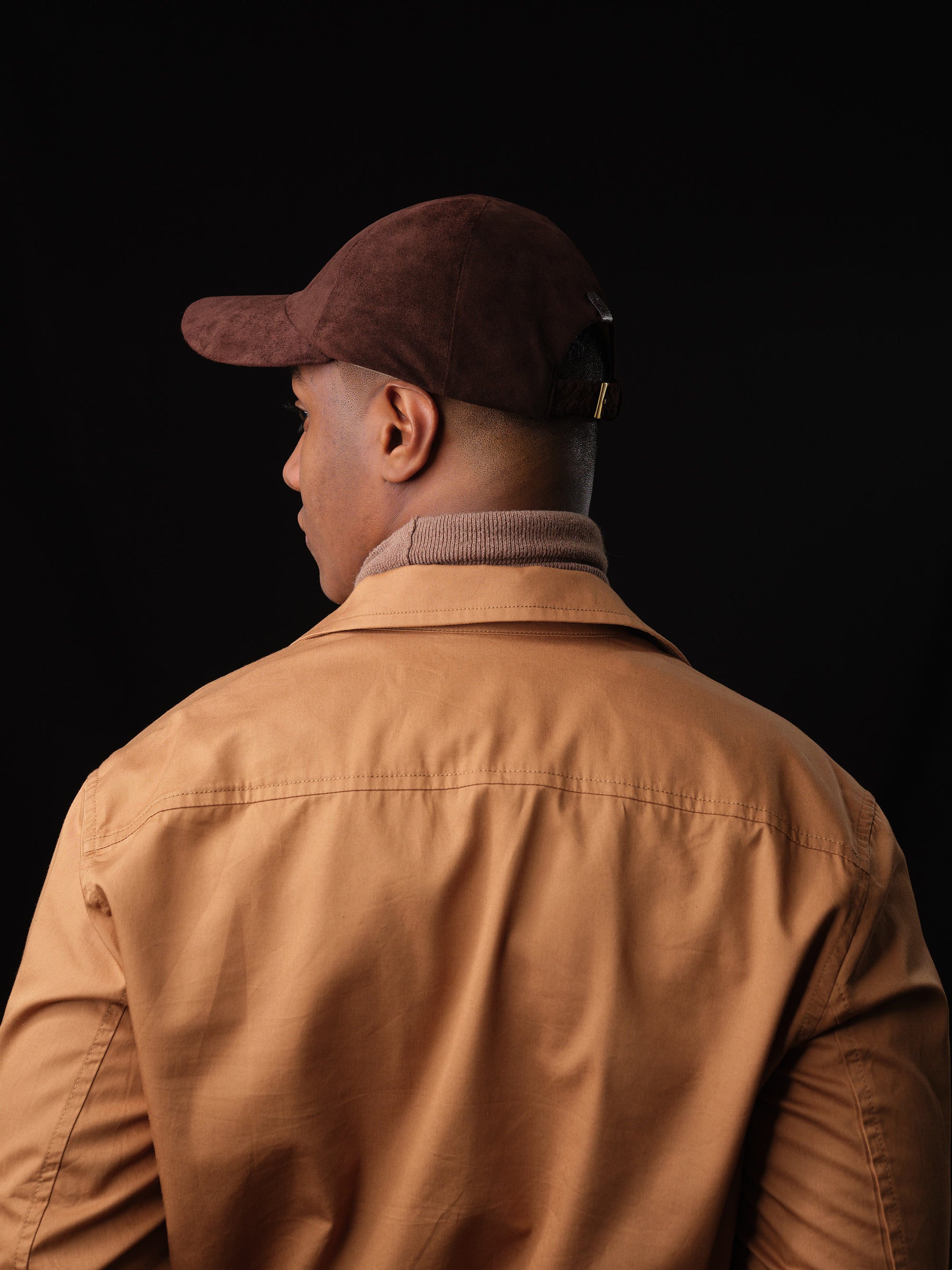 Stylish man wearing a brown suede baseball cap with ear flaps by Capra Leather 