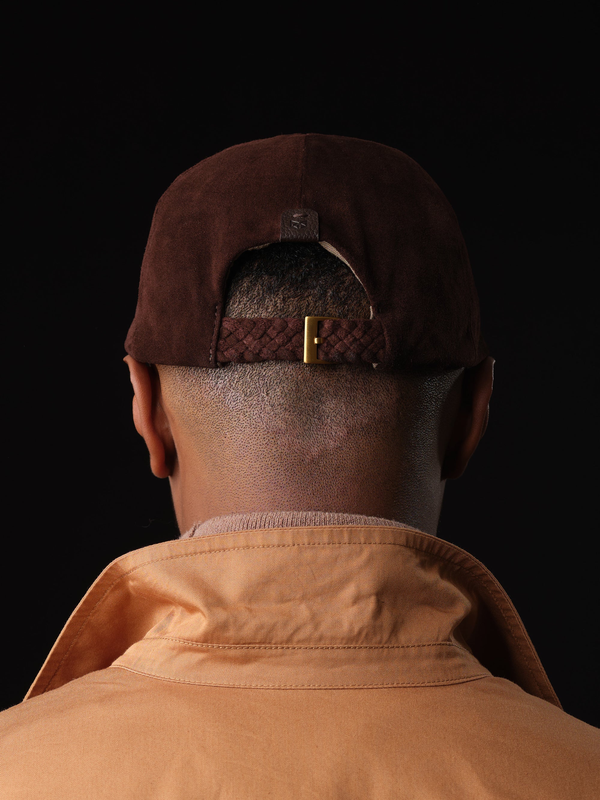 3Back view of a brown suede baseball cap with braided strap and buckle, handcrafted by Capra Leather