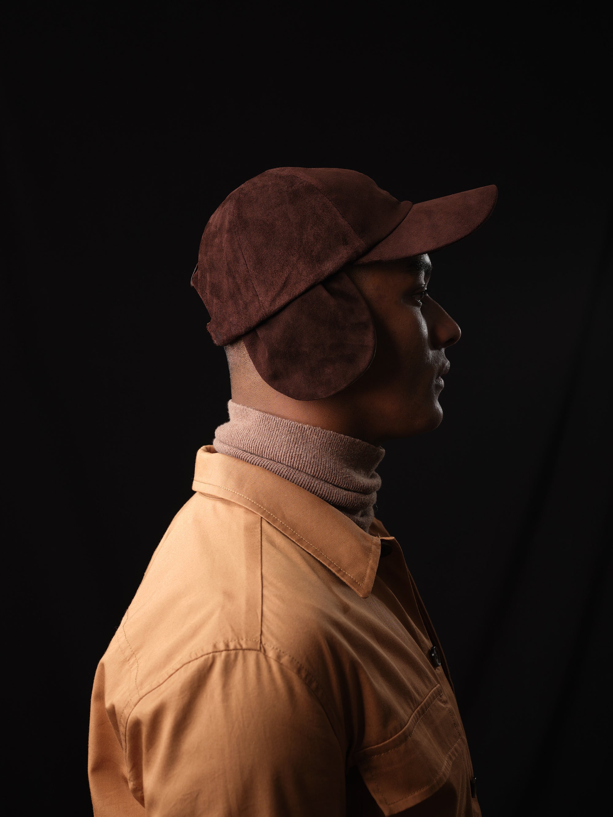 Studio shot of a man in a classic brown suede baseball cap with ear flaps