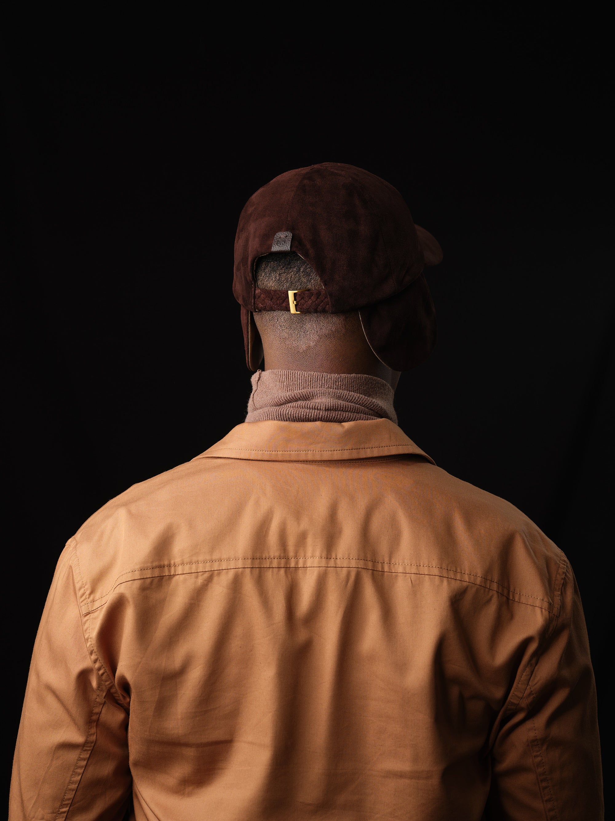 Man posing in a stylish brown suede baseball cap, handcrafted by Capra Leather