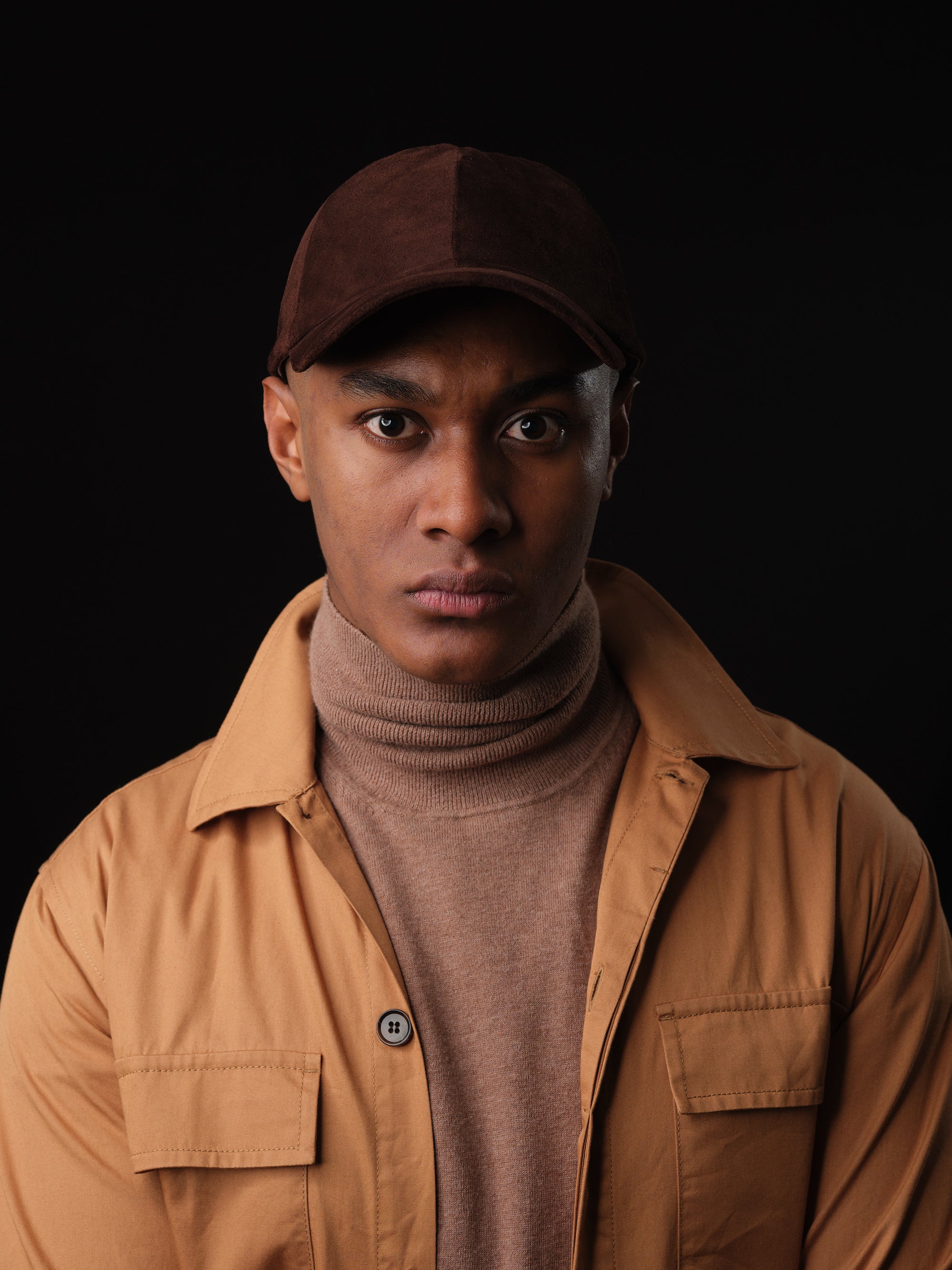 Man wearing a brown suede baseball cap, handcrafted by Capra Leather